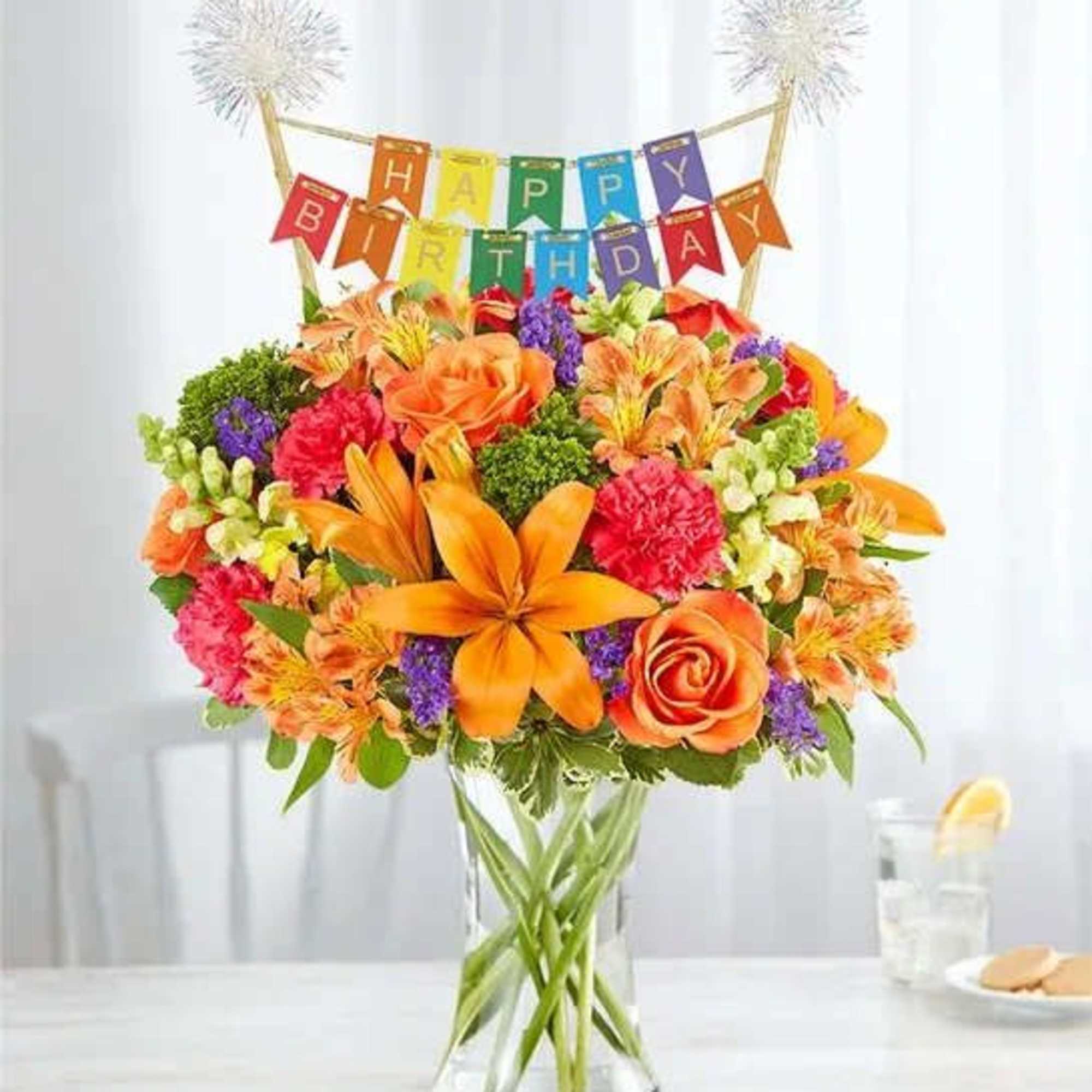 Colorful birthday bouquet in a clear glass vase with a banner topper