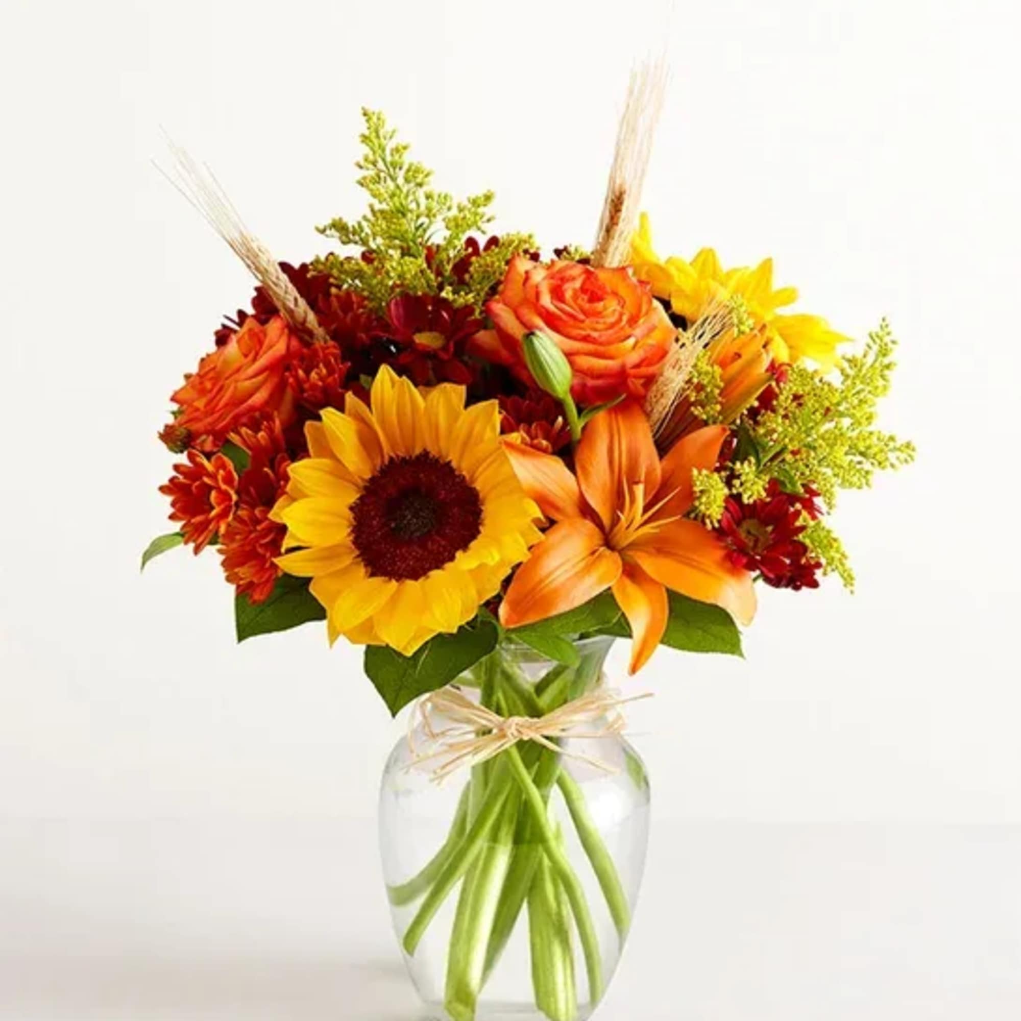 Sunflower and orange lily bouquet in a clear glass vase