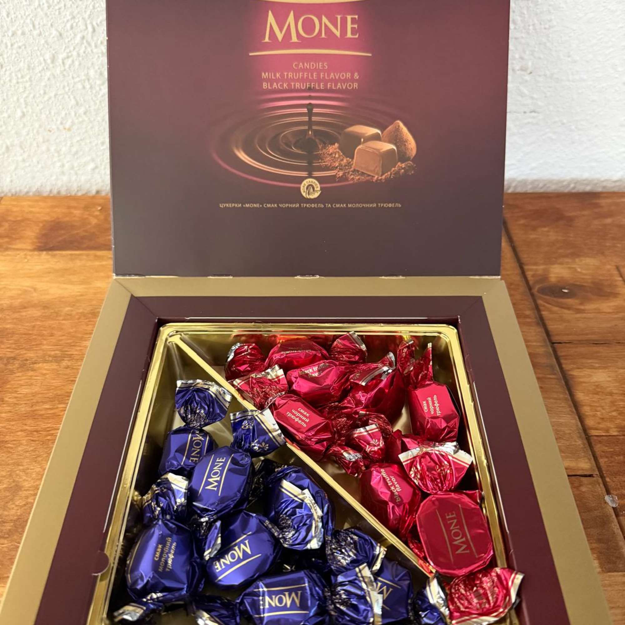 Open box of assorted wrapped chocolates in purple and red packaging