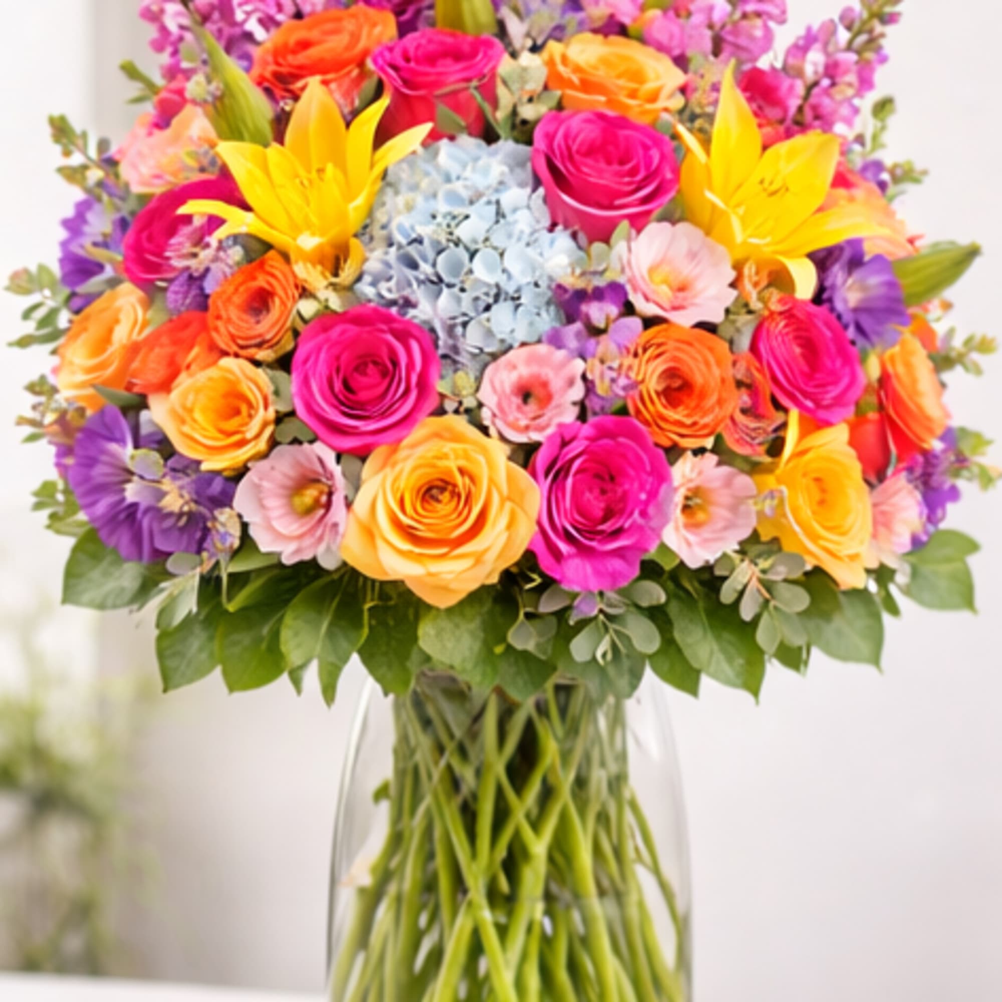 Colorful bouquet of roses, lilies, and hydrangea in a glass vase