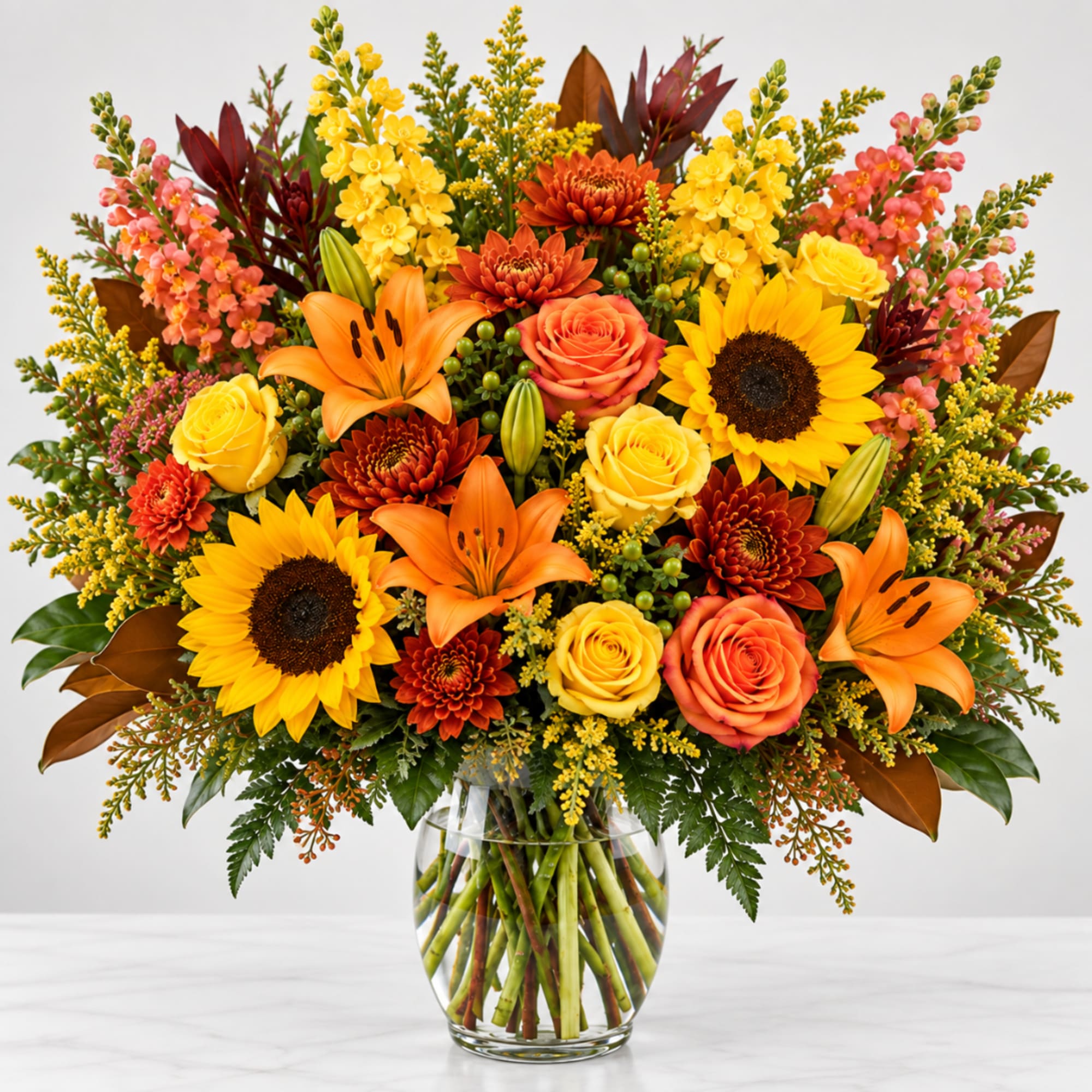 Bright mixed bouquet with sunflowers, roses, lilies, and mums in a clear glass vase