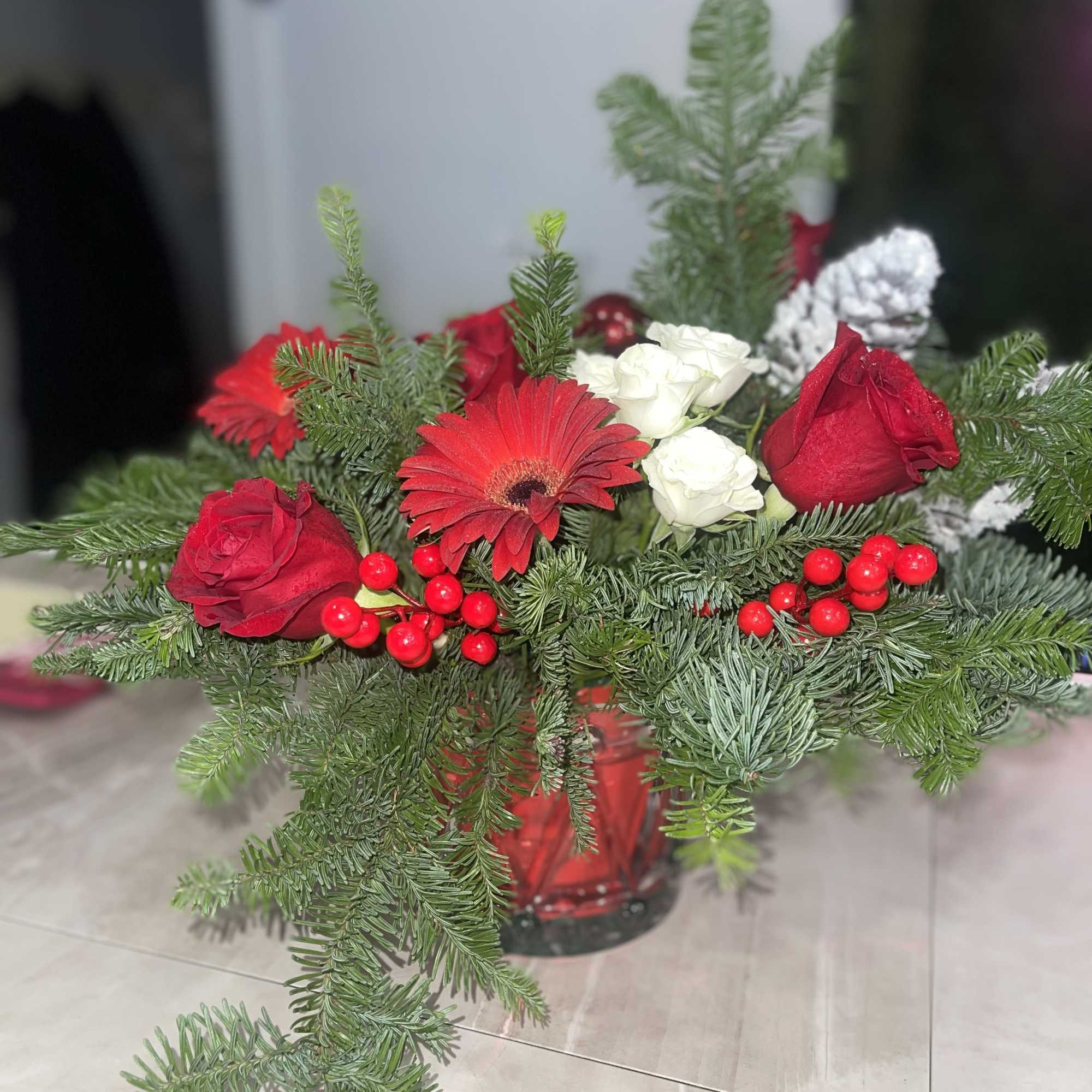 Red and white roses with a red gerbera in a glass vase