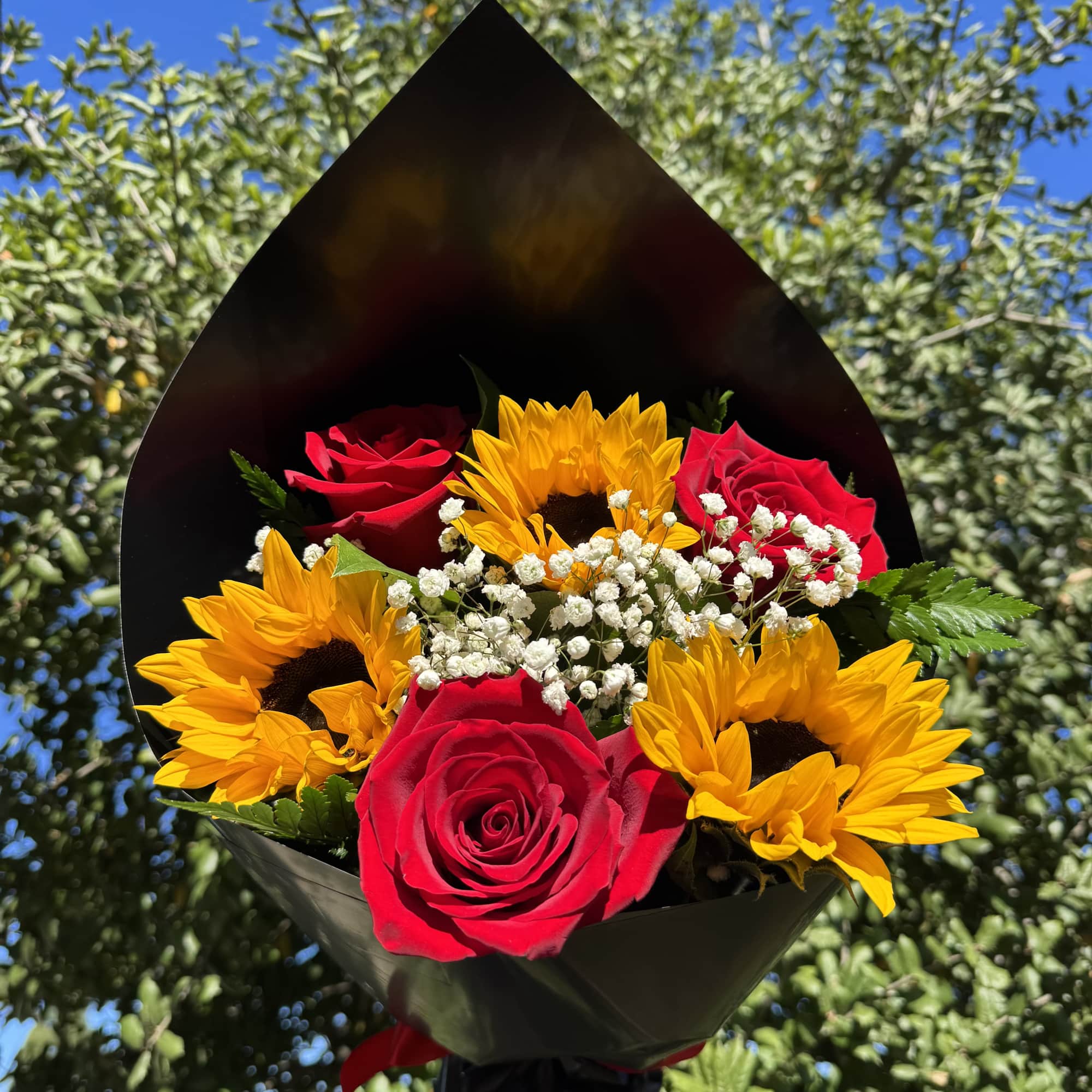 Bouquet of red roses and yellow sunflowers in black wrap