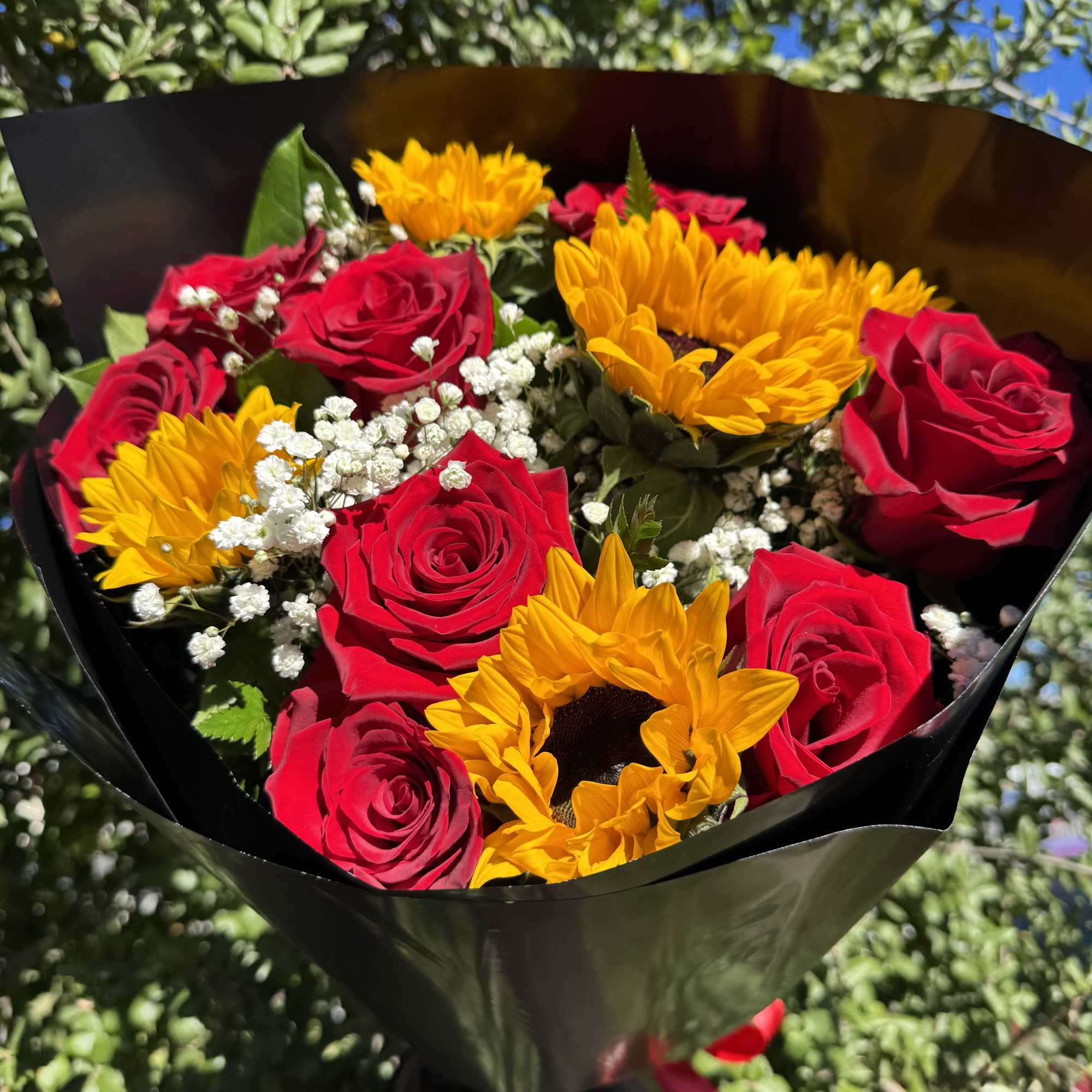 Bouquet of red roses and yellow sunflowers wrapped in black paper