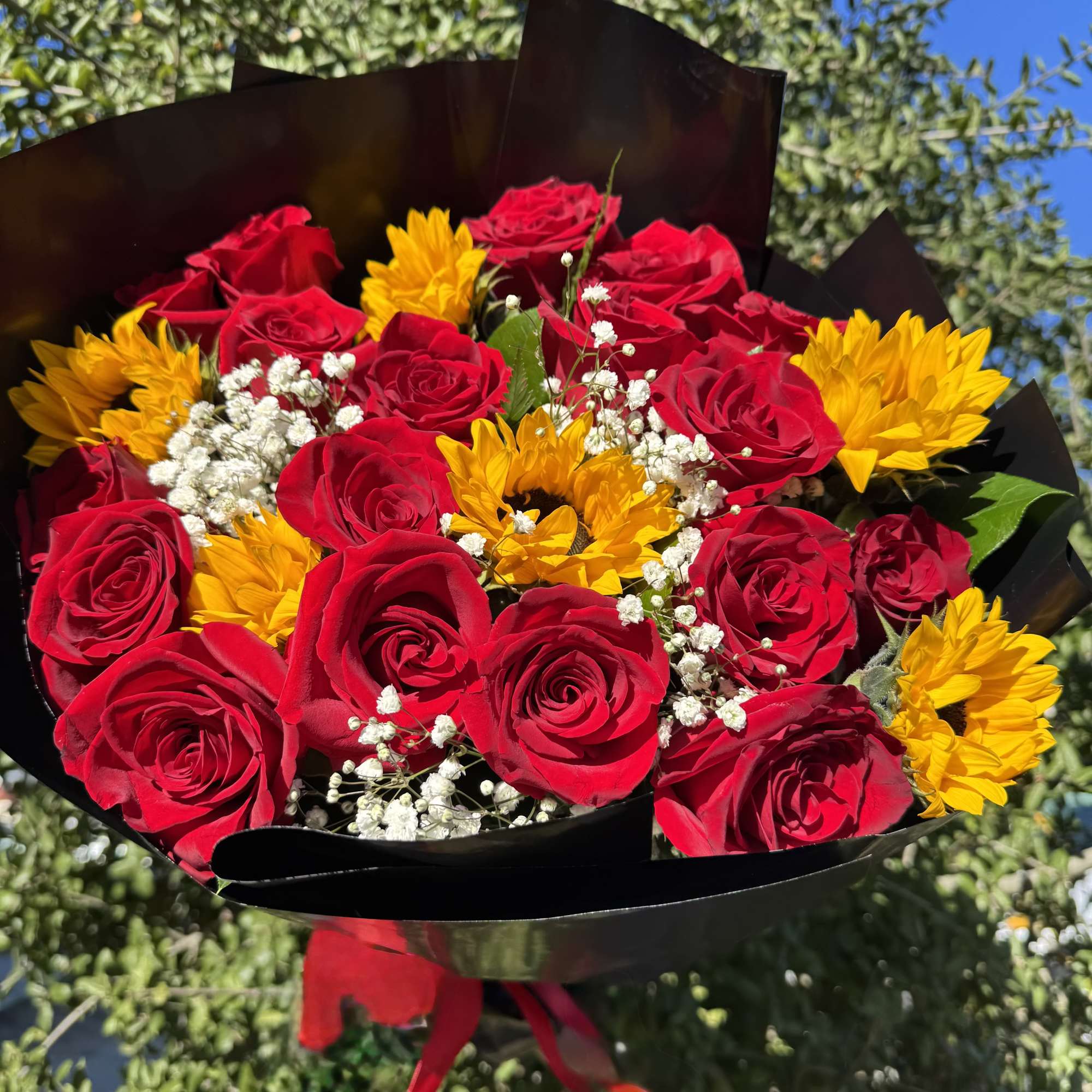Bouquet of red roses and yellow sunflowers wrapped in black paper
