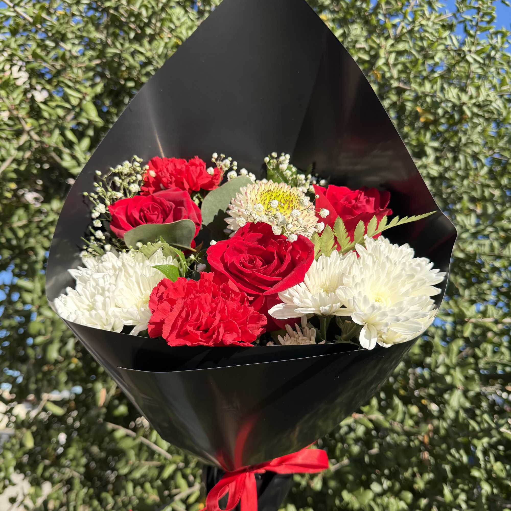 Bouquet of red roses and white chrysanthemums wrapped in black paper
