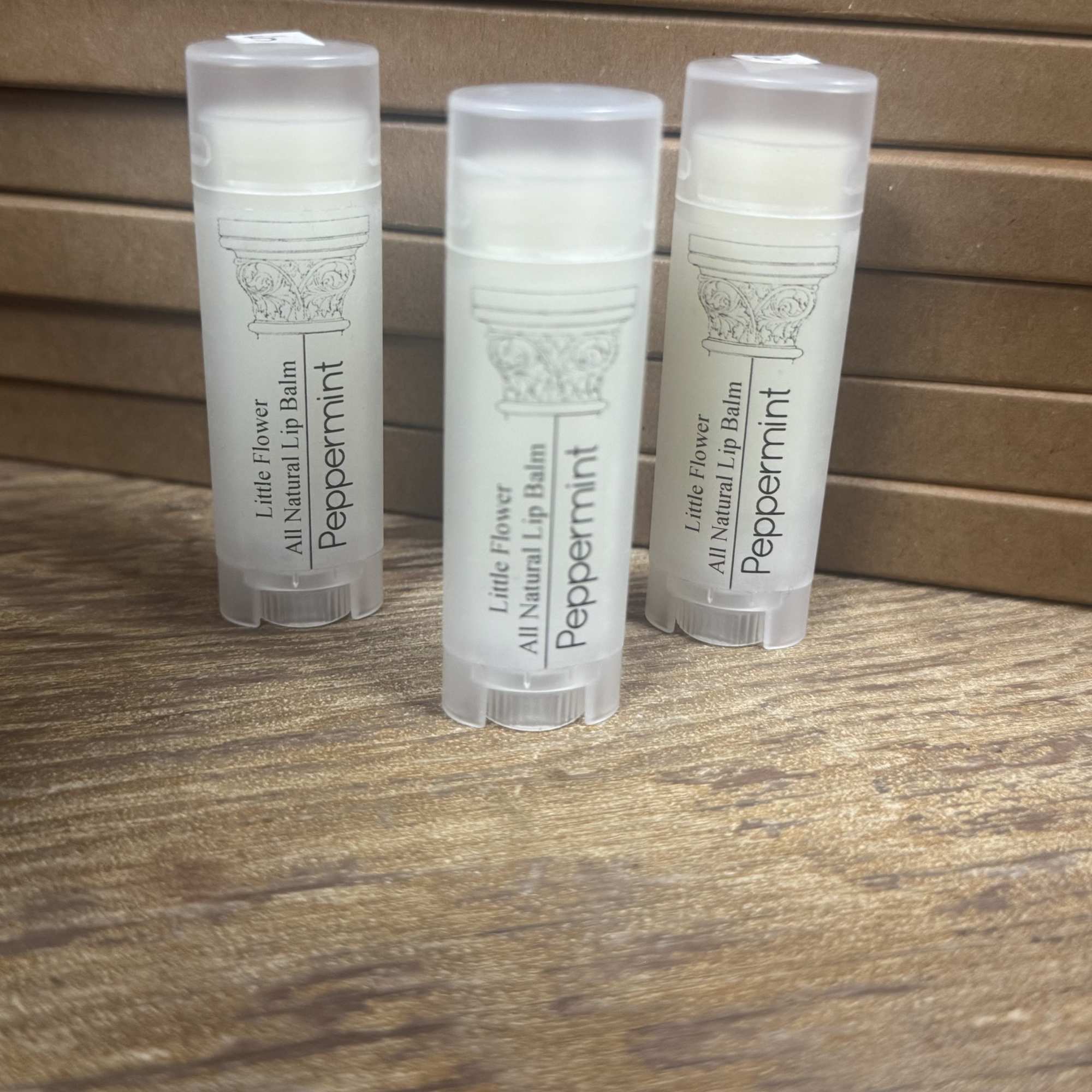 Three peppermint lip balm tubes on a wooden surface