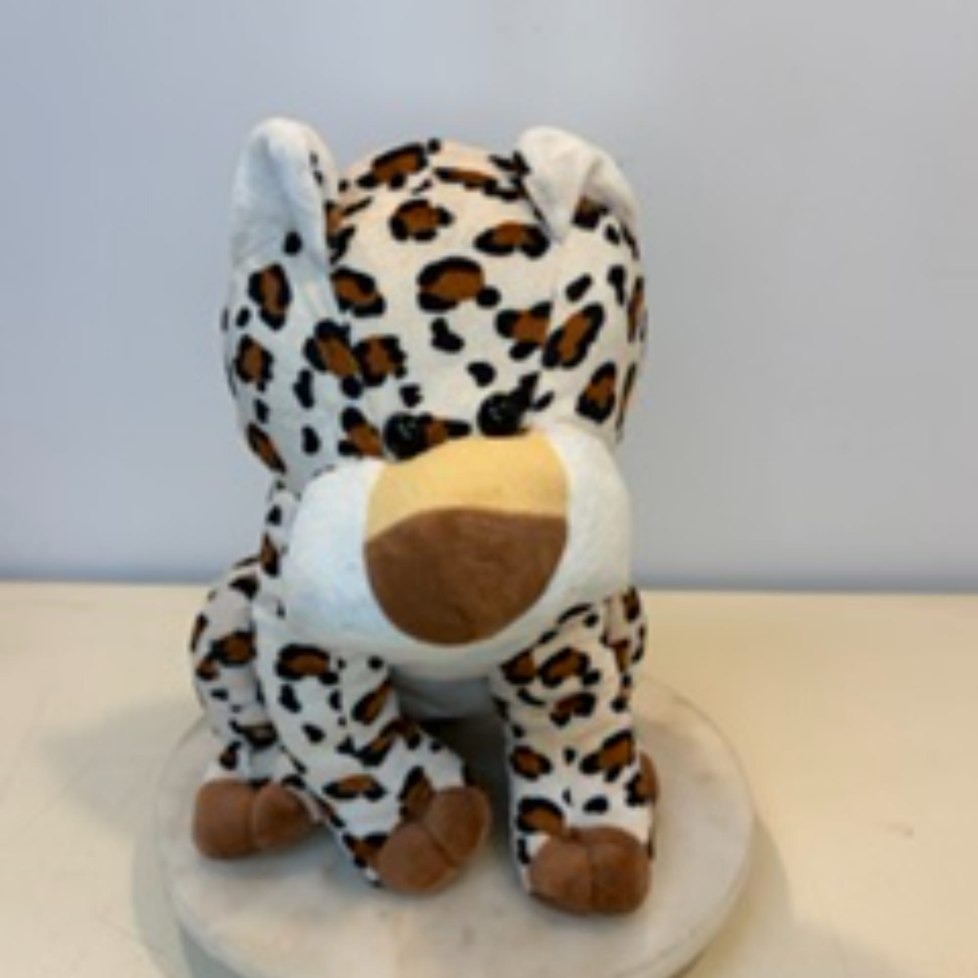 Plush leopard-print dog sitting on a round base