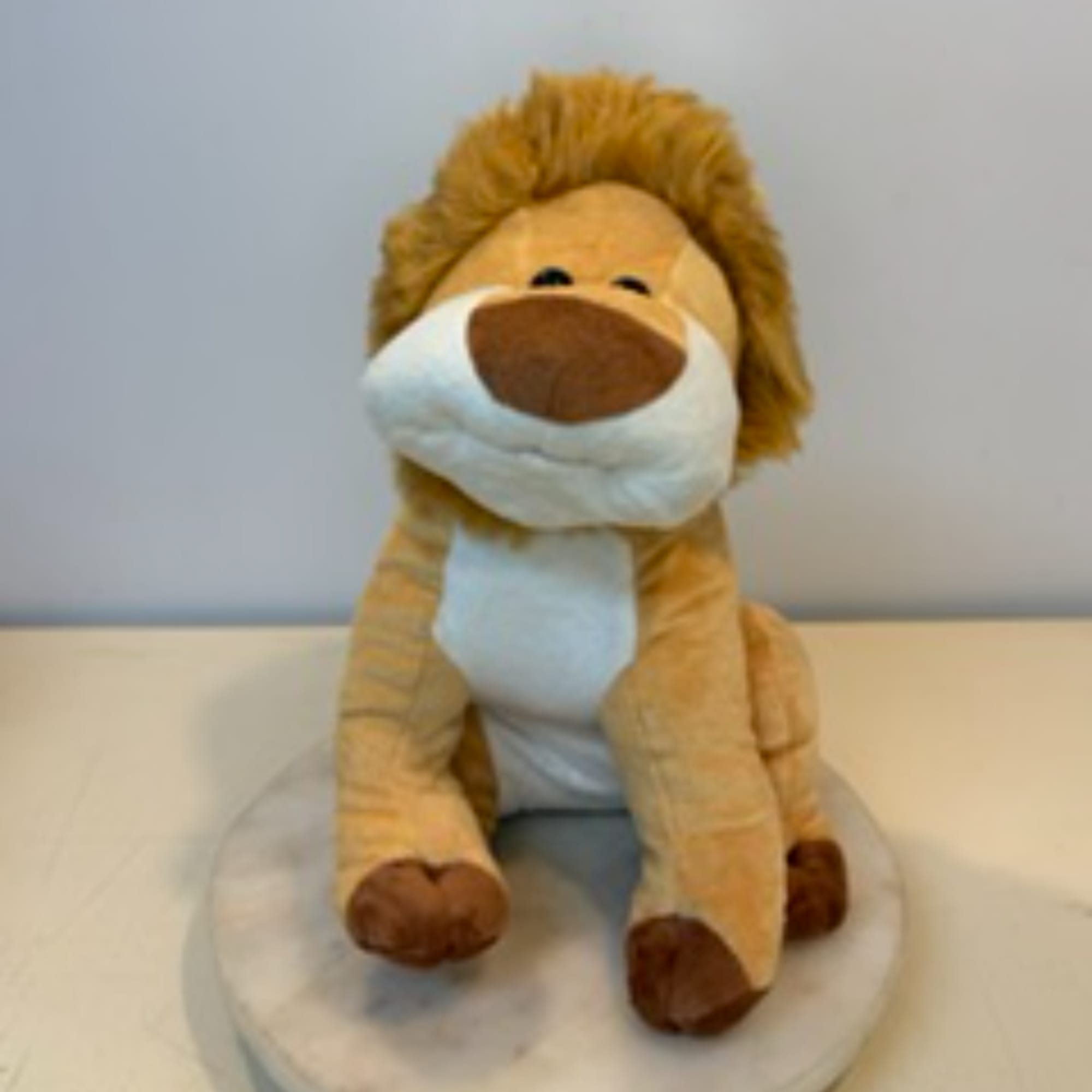Plush lion toy sitting on a round white cushion