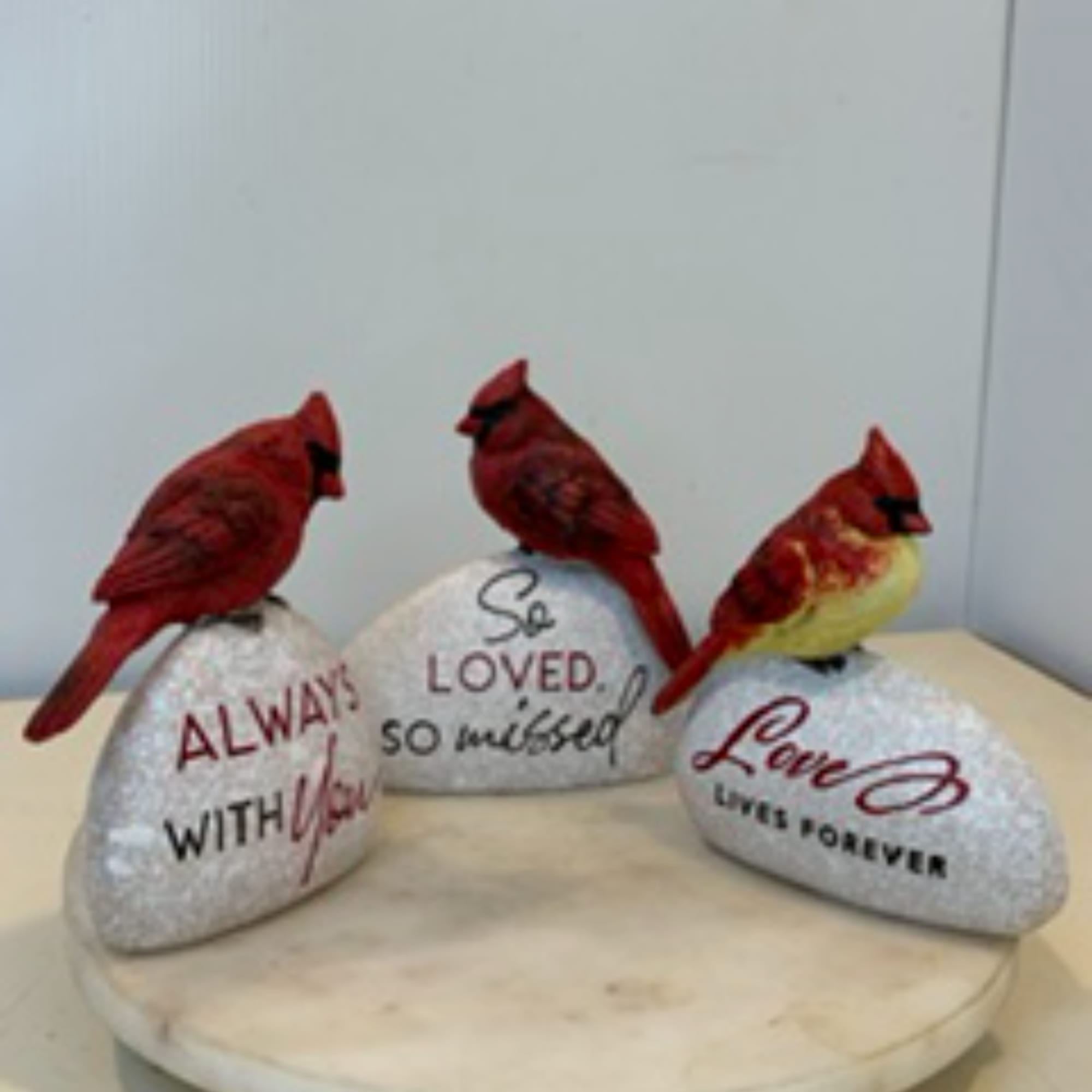 Three decorative cardinal figurines on painted stones with memorial text