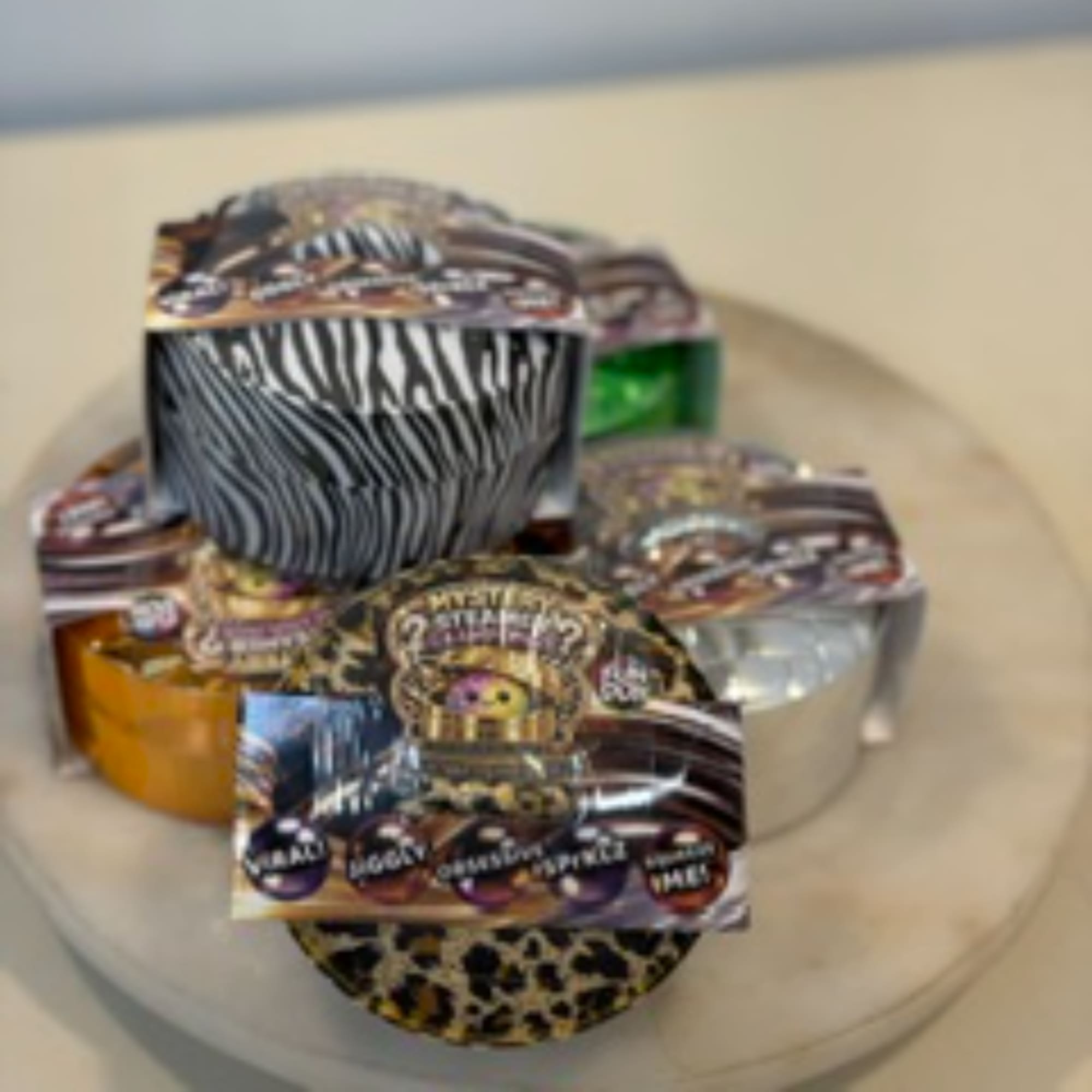 Assorted small gift tins with animal-print lids on a plate