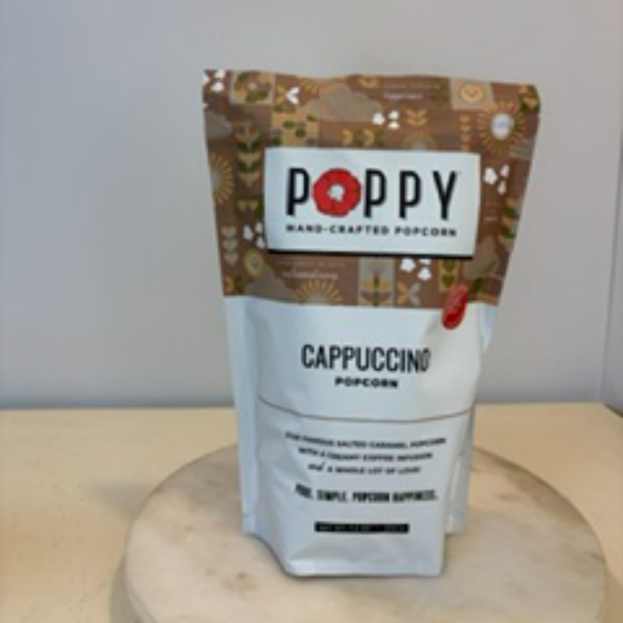 Bag of Poppy cappuccino popcorn on a round display stand