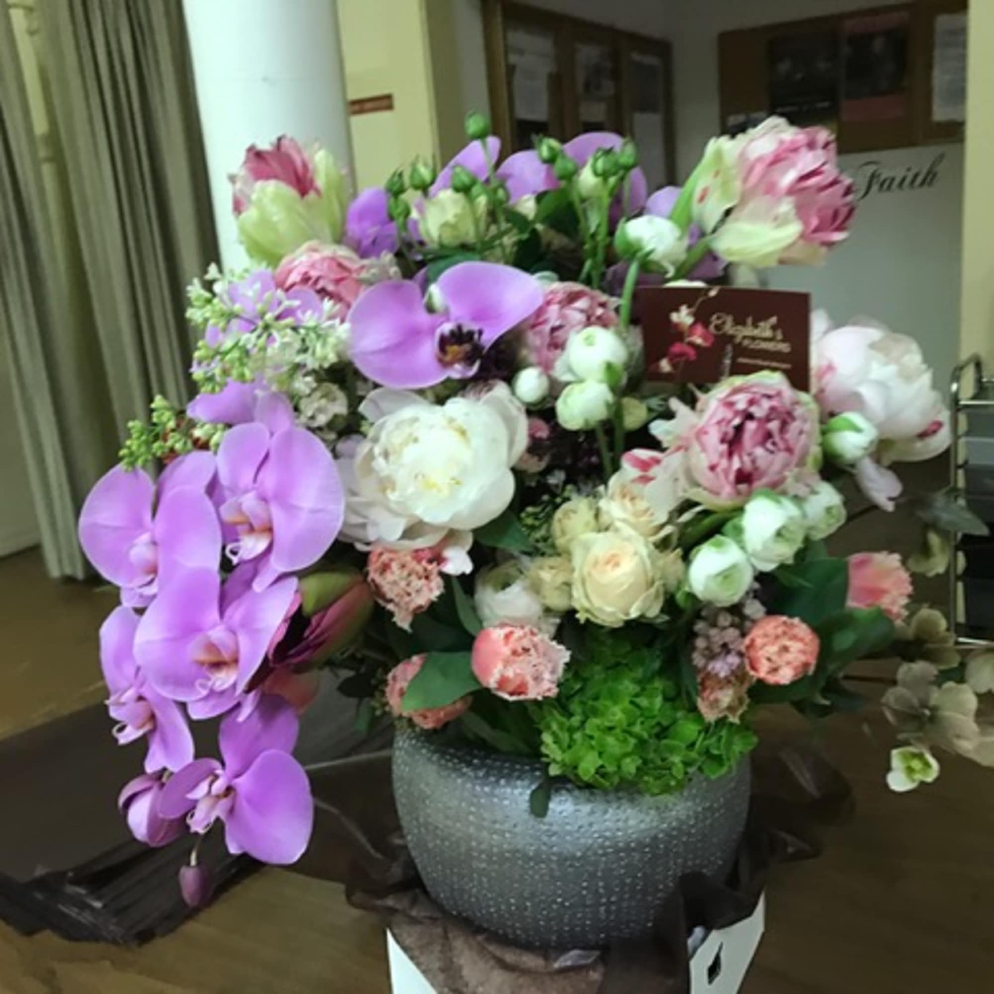 Purple orchids and pink-white flowers arranged in a gray vase