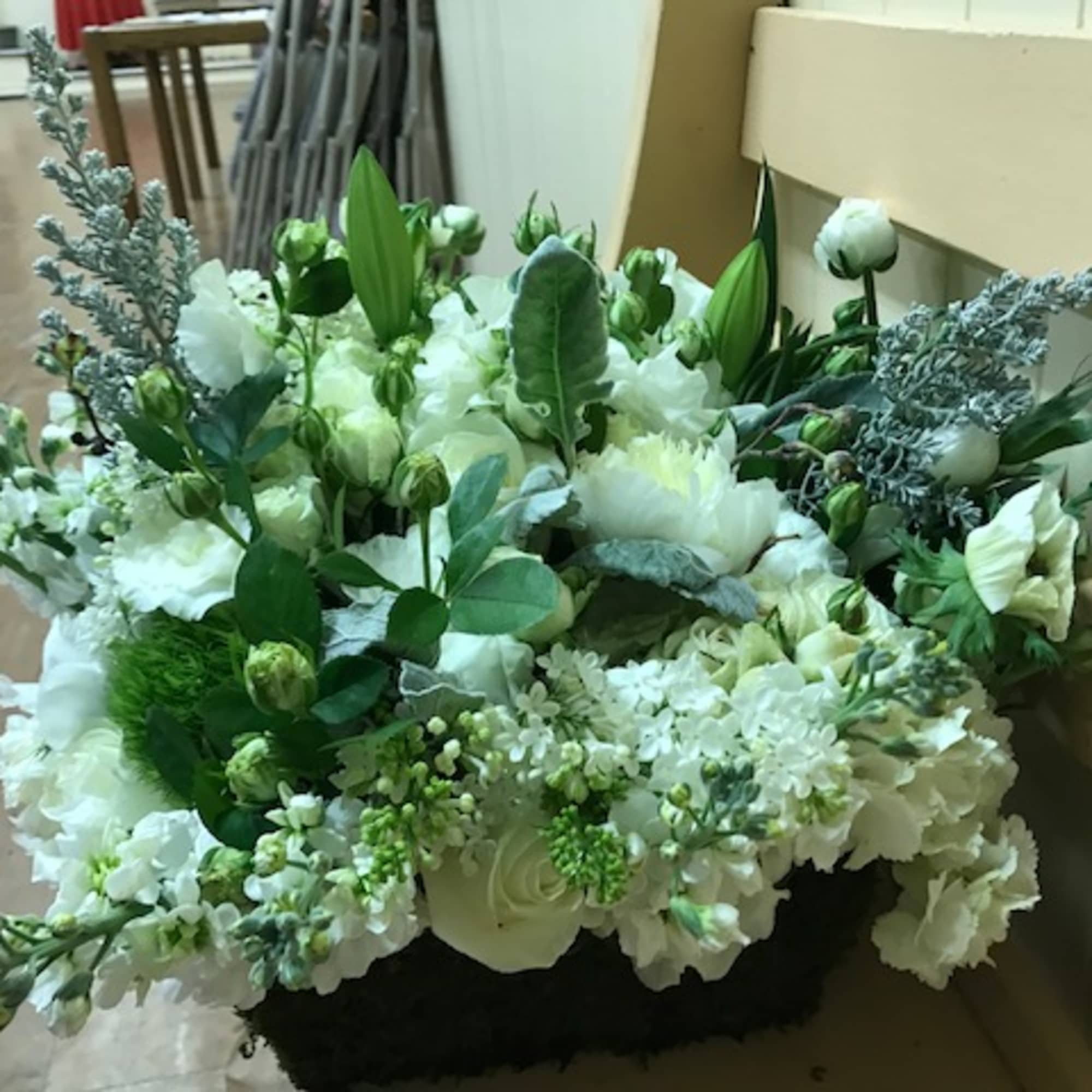 Large white floral arrangement with mixed blooms in a black container