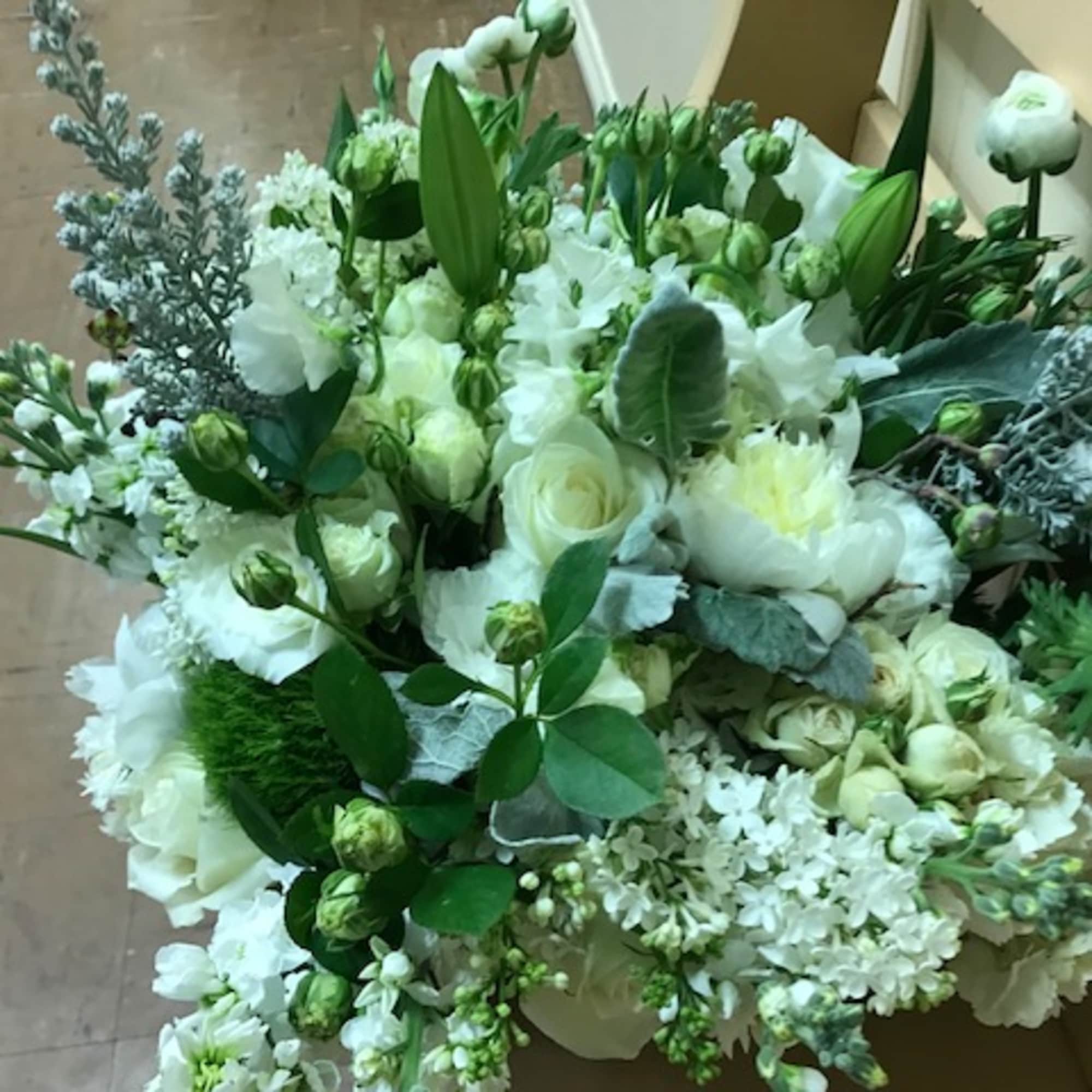 White floral arrangement with roses, lilies, and mixed blooms
