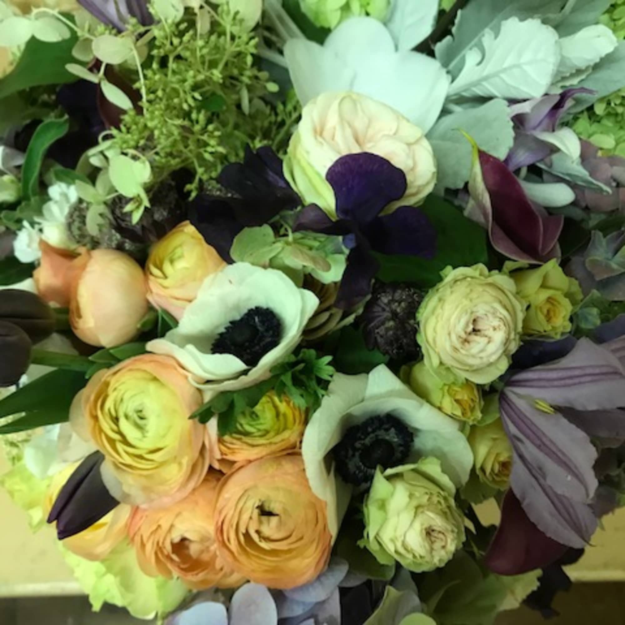 Bouquet of pale peach, white, and dark purple flowers