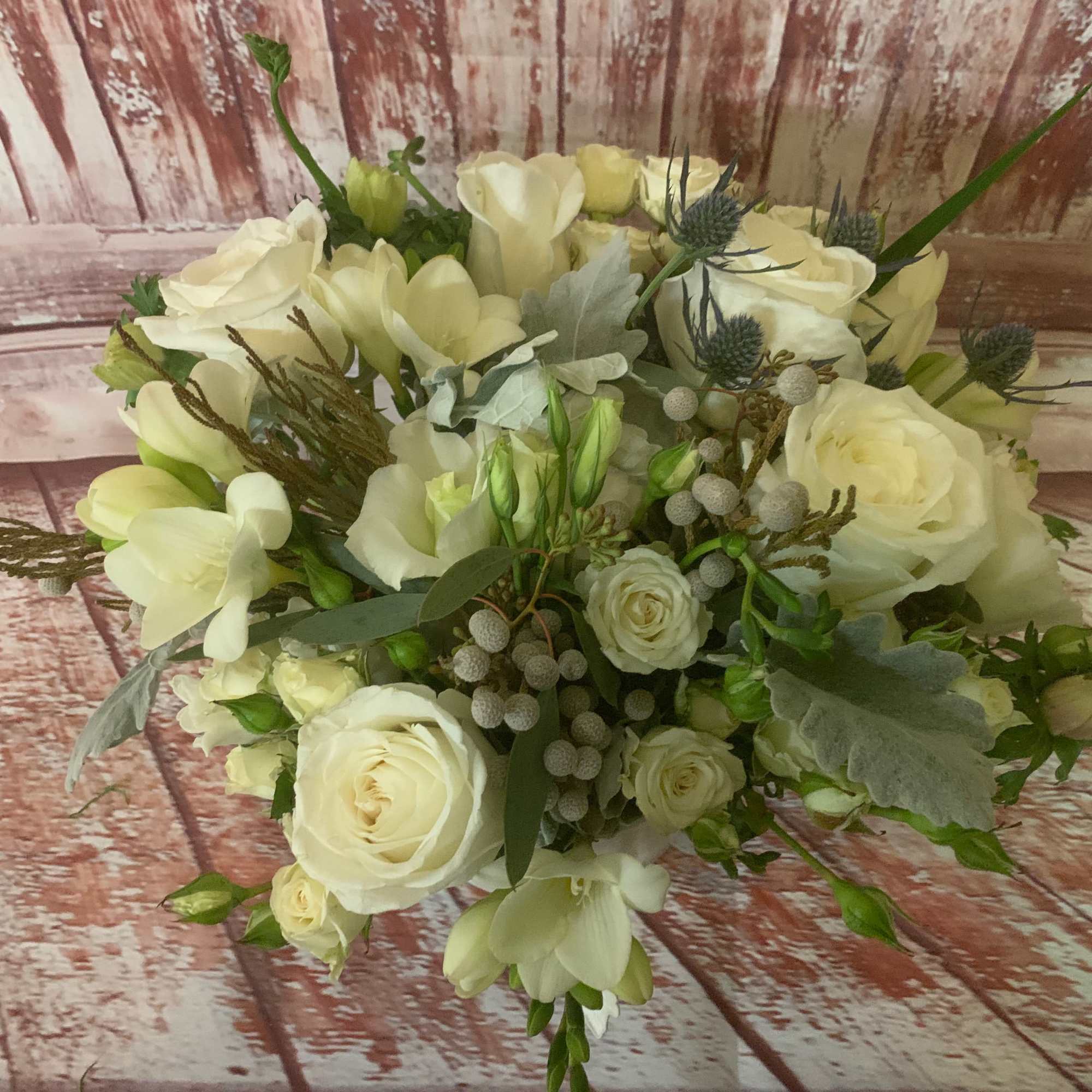 Floral arrangement in elegant white and cream hues presented in a clear