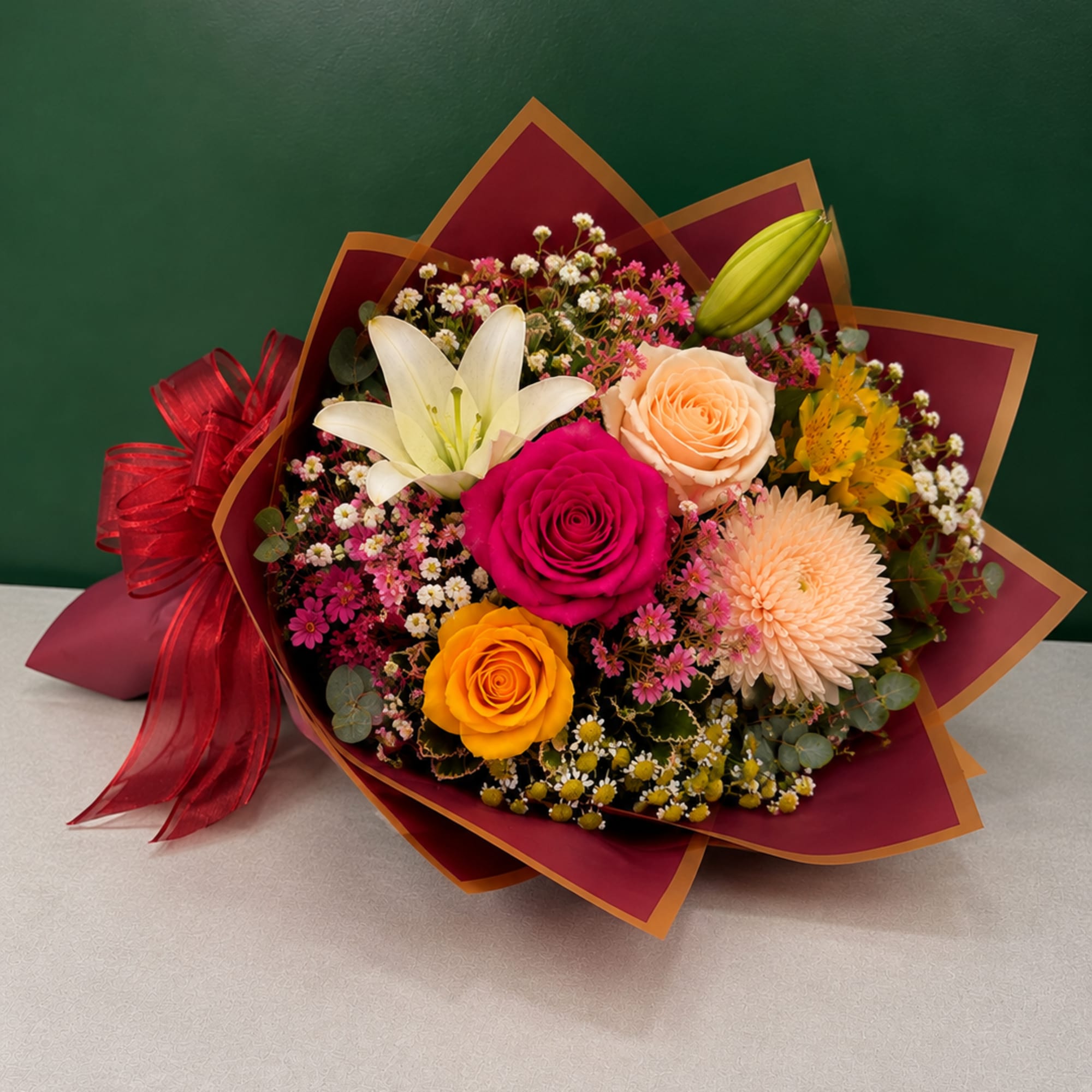 Mixed bouquet with roses, lilies, and a chrysanthemum wrapped in burgundy paper