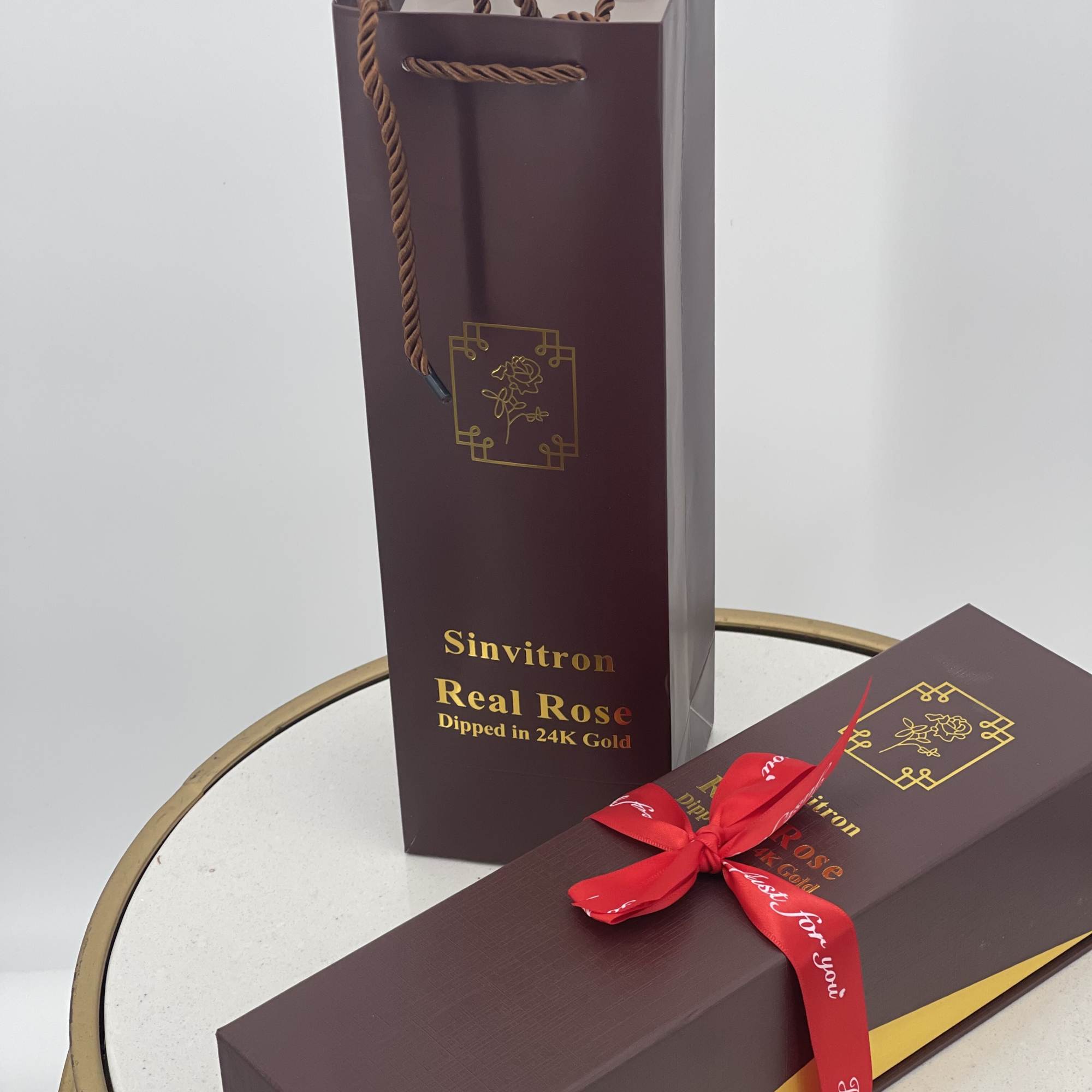 Two burgundy gift boxes with a red ribbon, one standing upright and one lying flat.