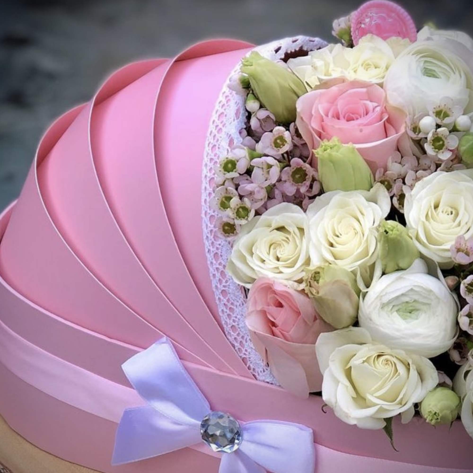 Pink hatbox bouquet of white and blush roses with a lavender ribbon