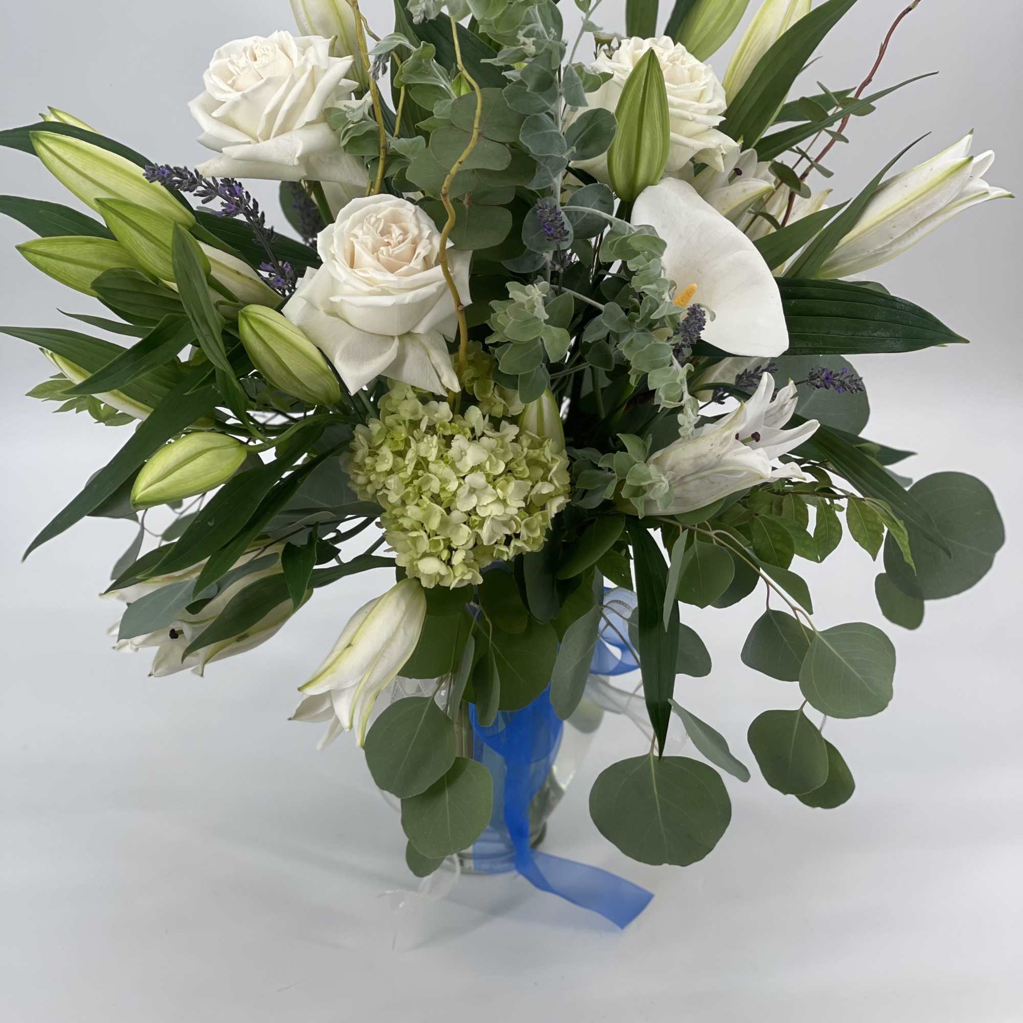 White roses and lilies arranged in a blue glass vase