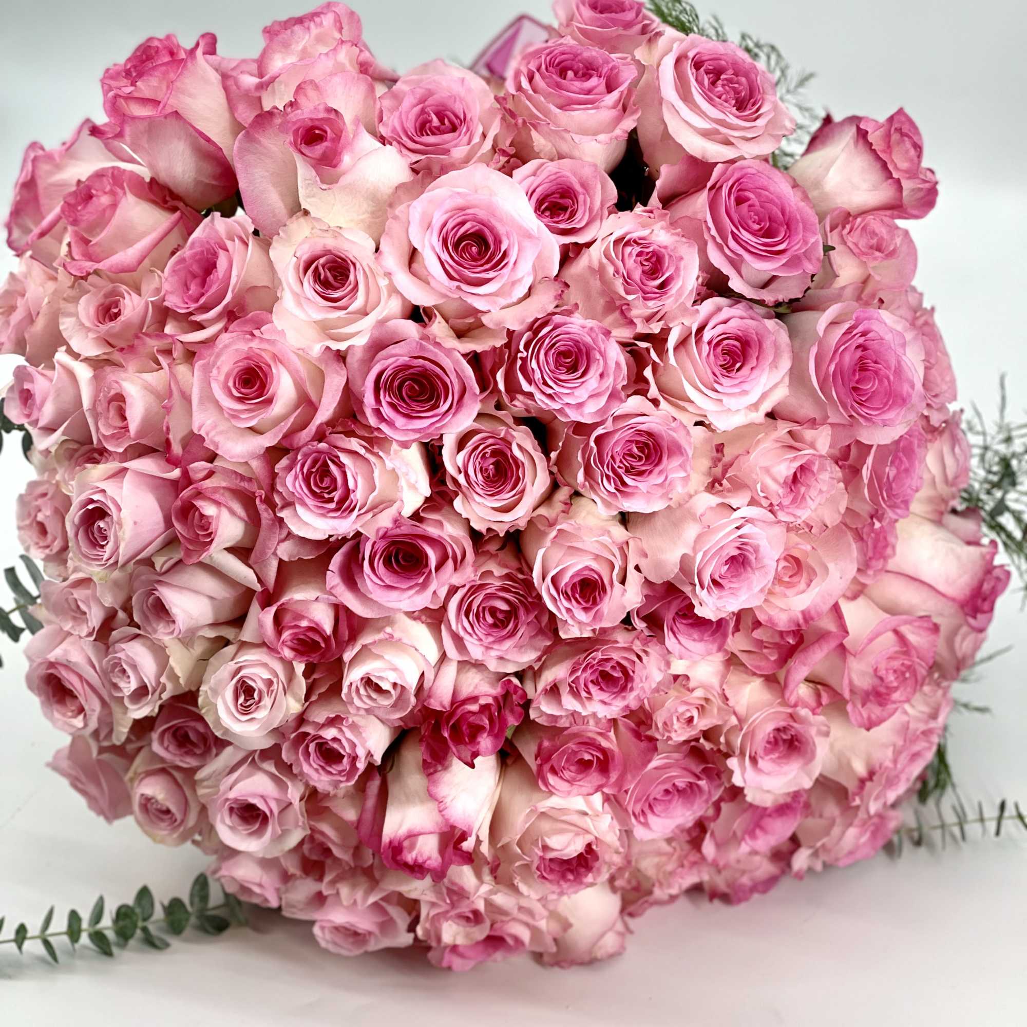 Large bouquet of pink roses with a few sprigs of greenery
