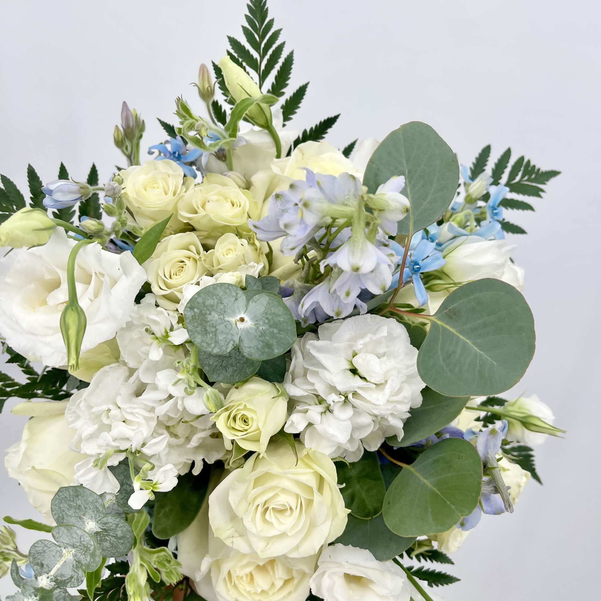 Bouquet of white roses and pale blue flowers with eucalyptus