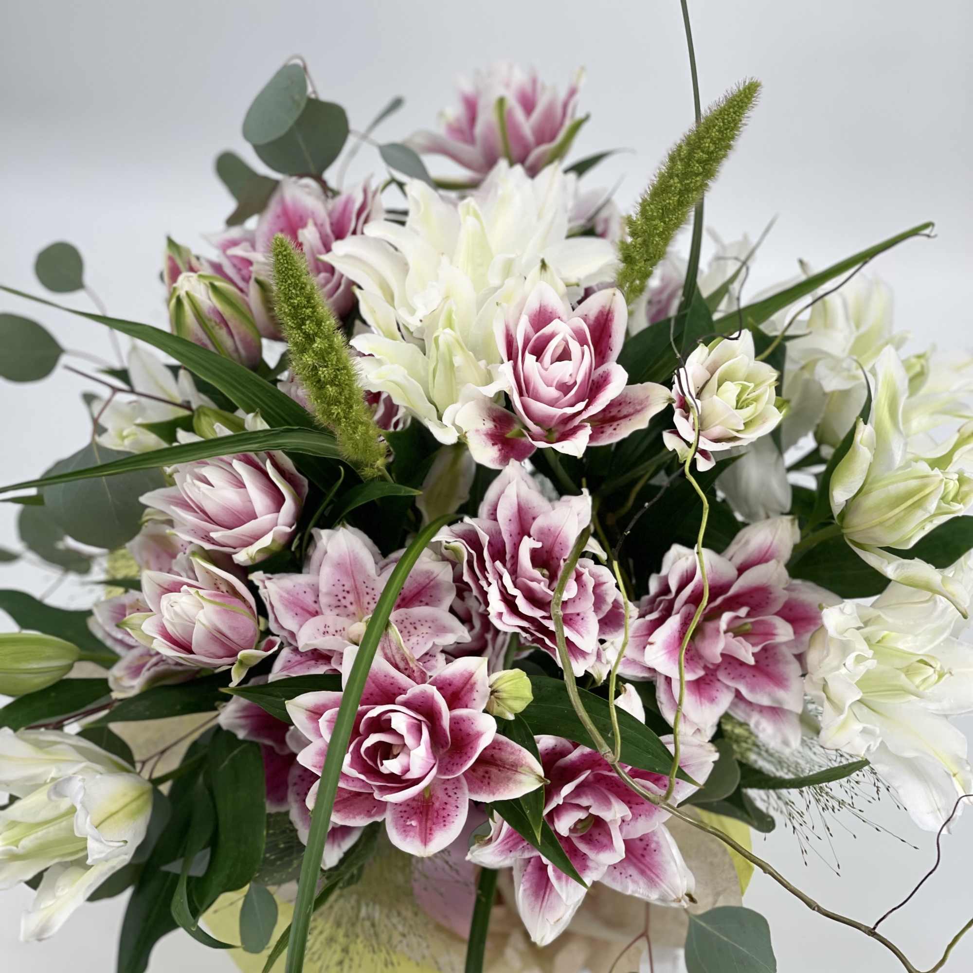 Pink and white lilies arranged in a bouquet with greenery