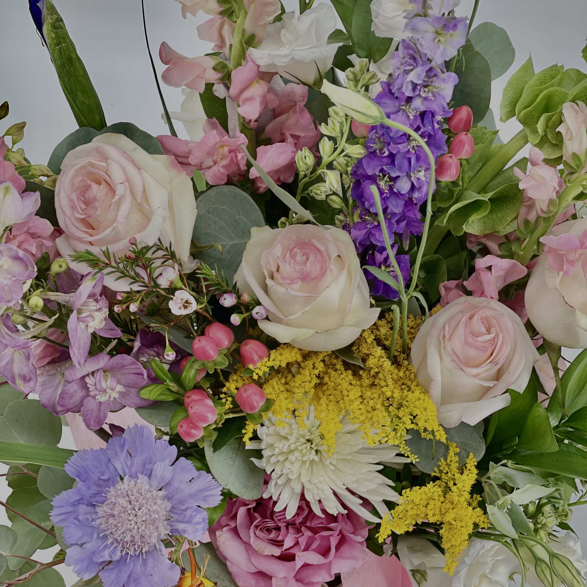 Mixed bouquet of pink roses, purple blooms, and white flowers