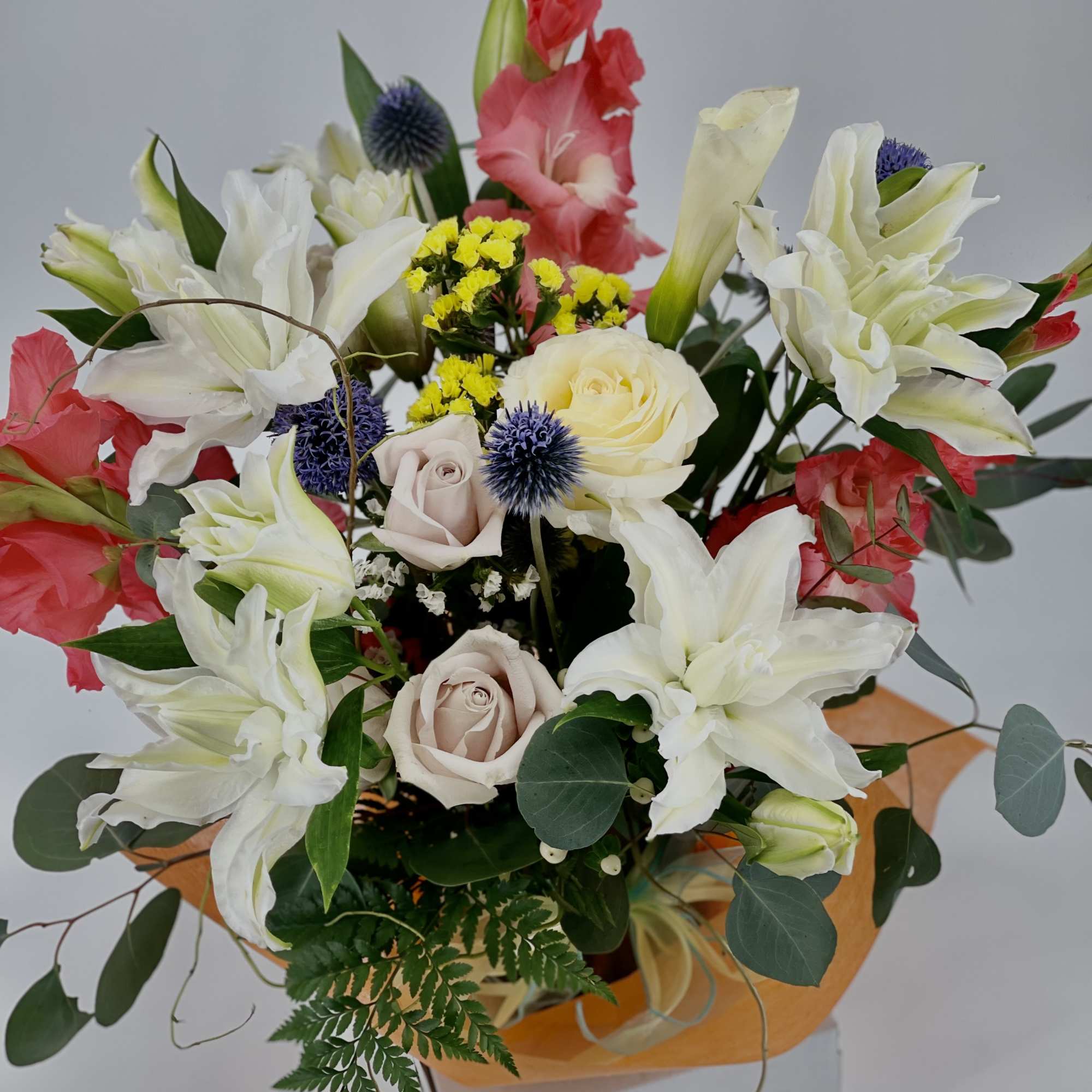 Mixed bouquet with white lilies, roses, and red gladiolus in a box