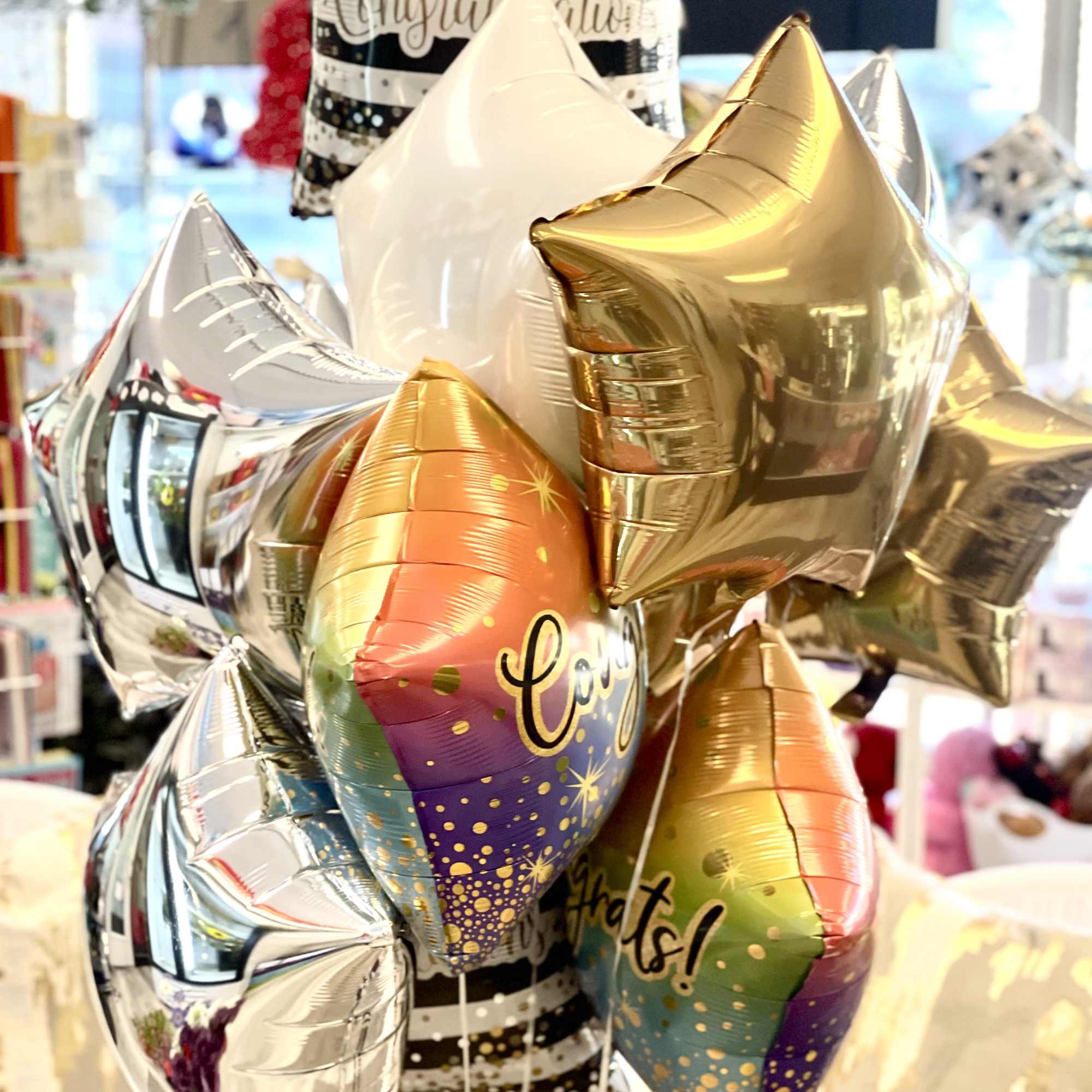 Cluster of metallic star-shaped balloons with a congratulatory balloon behind them
