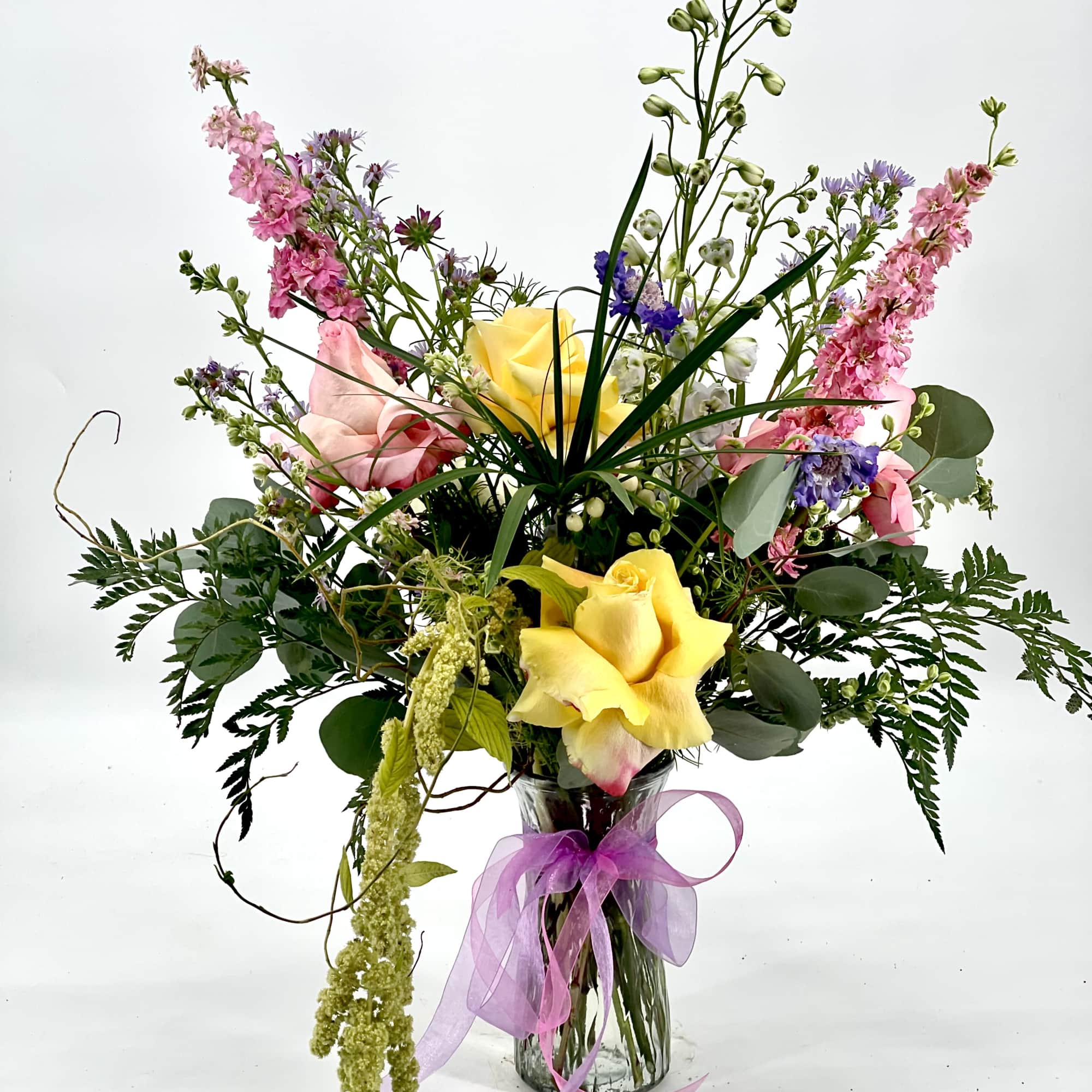 Tall mixed bouquet in a glass vase with yellow and pink roses