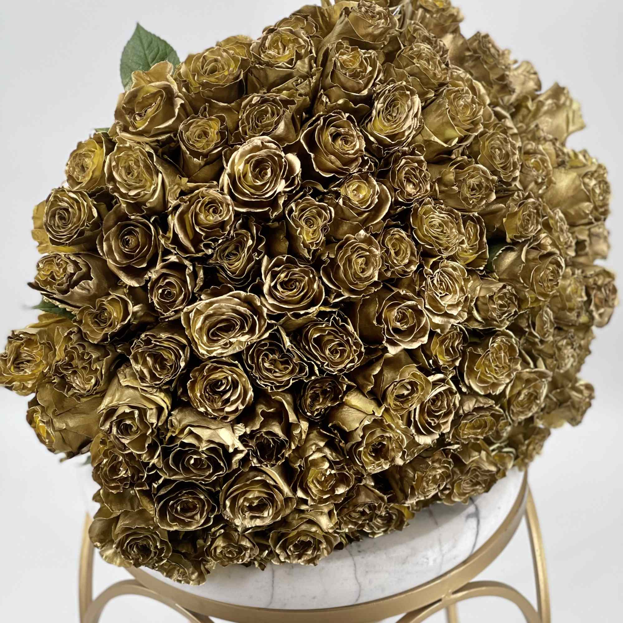 A dense bouquet of gold-colored roses on a stand