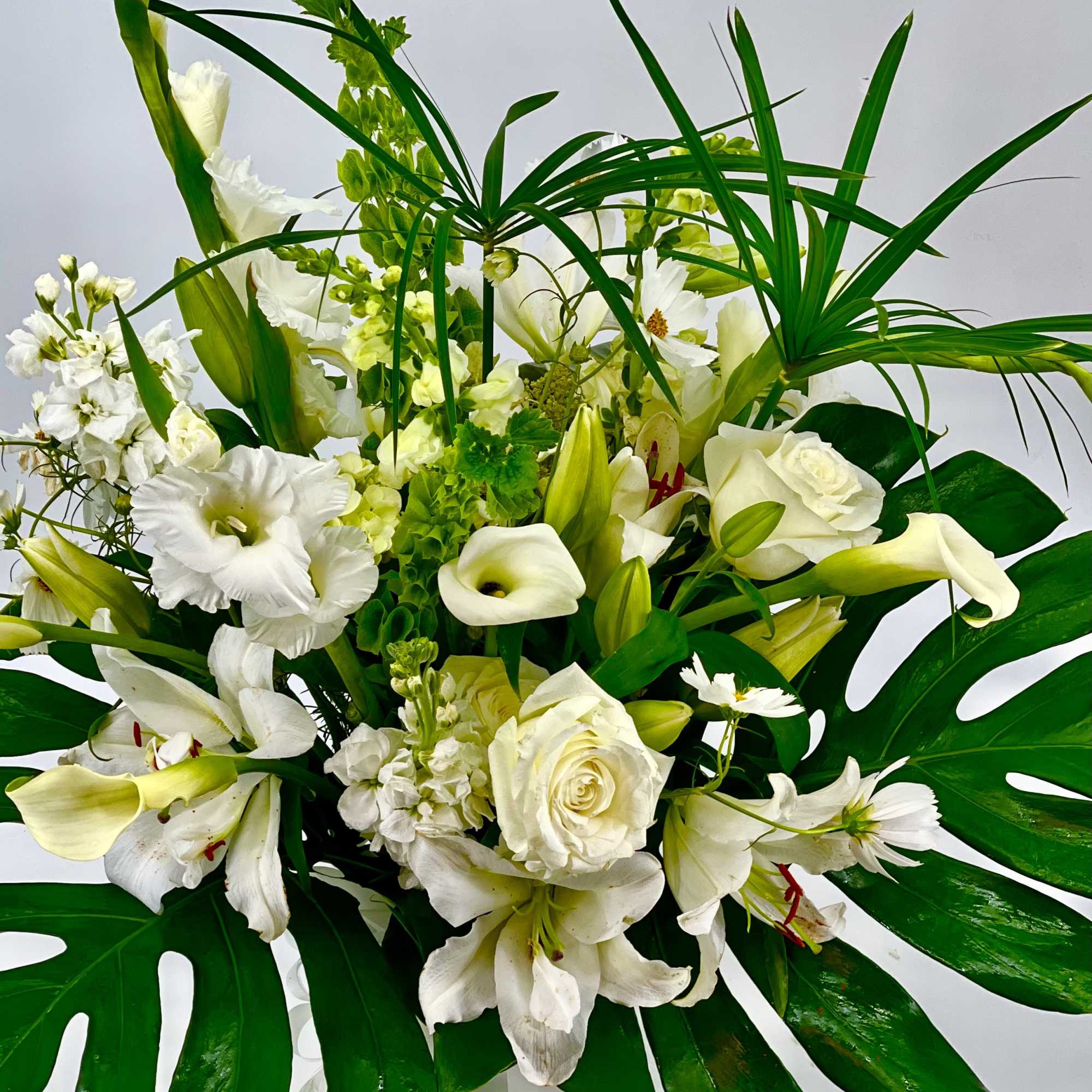 White floral arrangement with roses, lilies, and calla lilies