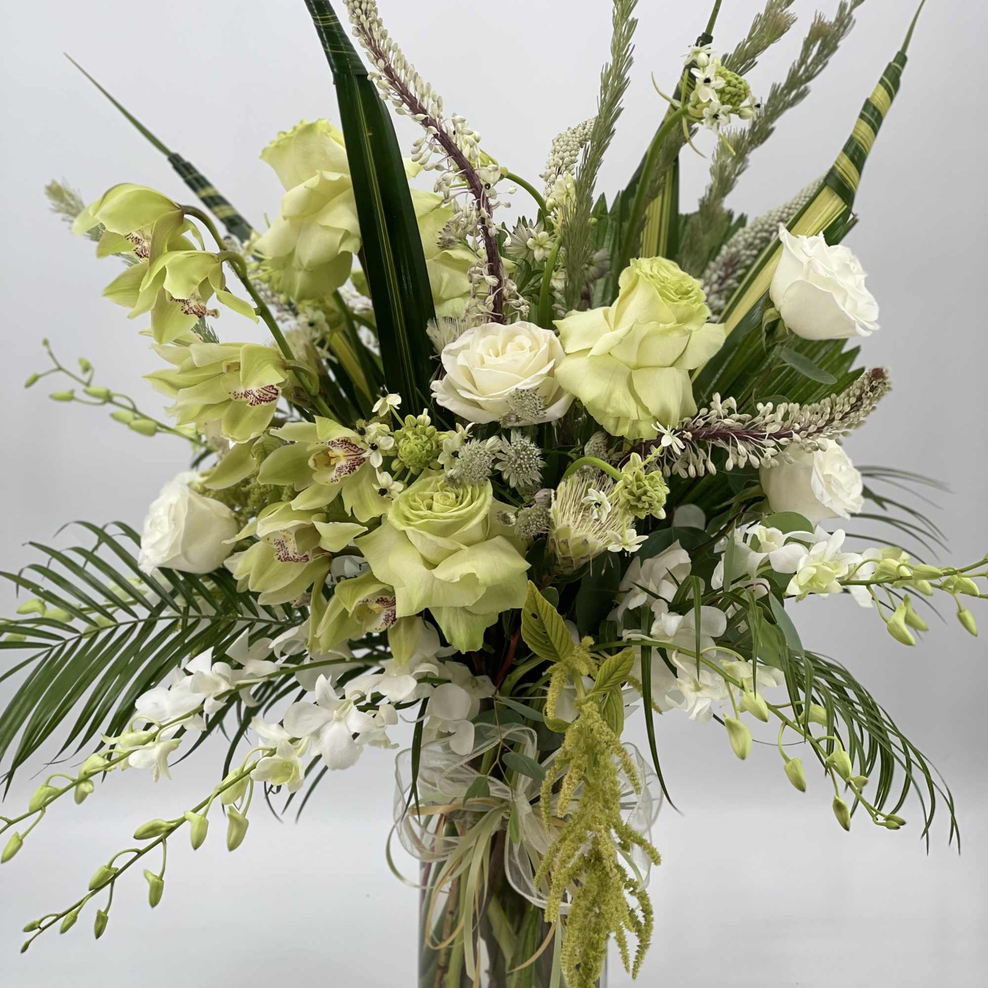 Tall green and white floral arrangement in a clear glass vase
