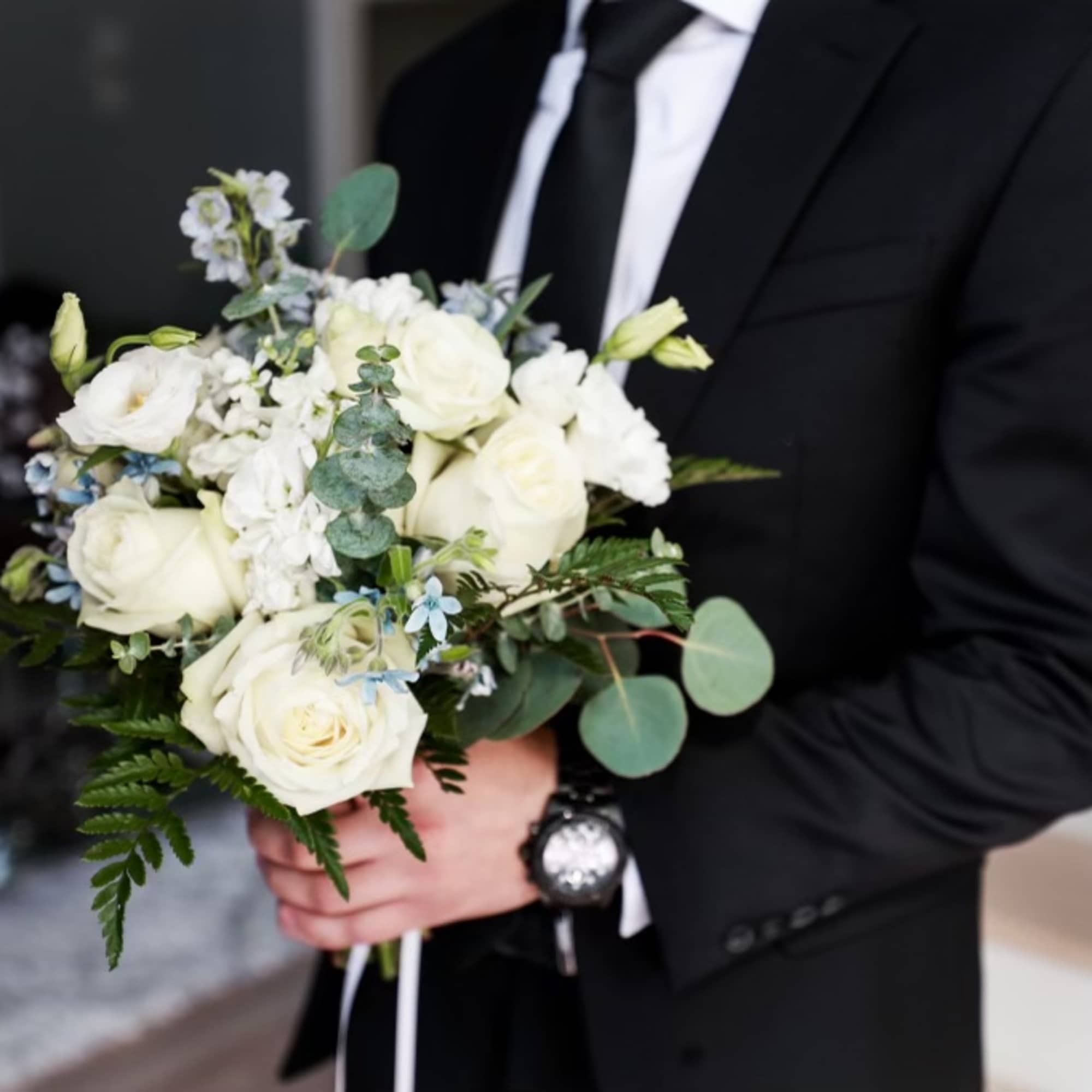 Man in a suit holding a white rose bouquet