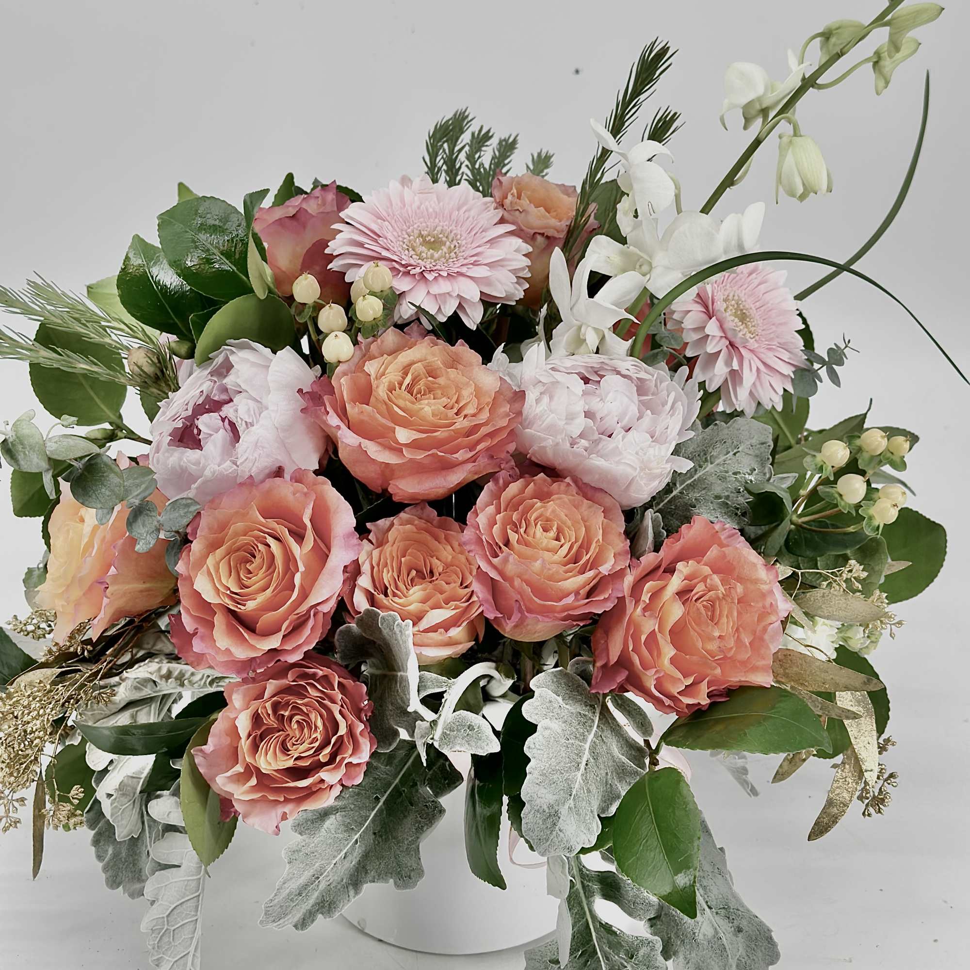 Pink and peach roses with white flowers in a white vase