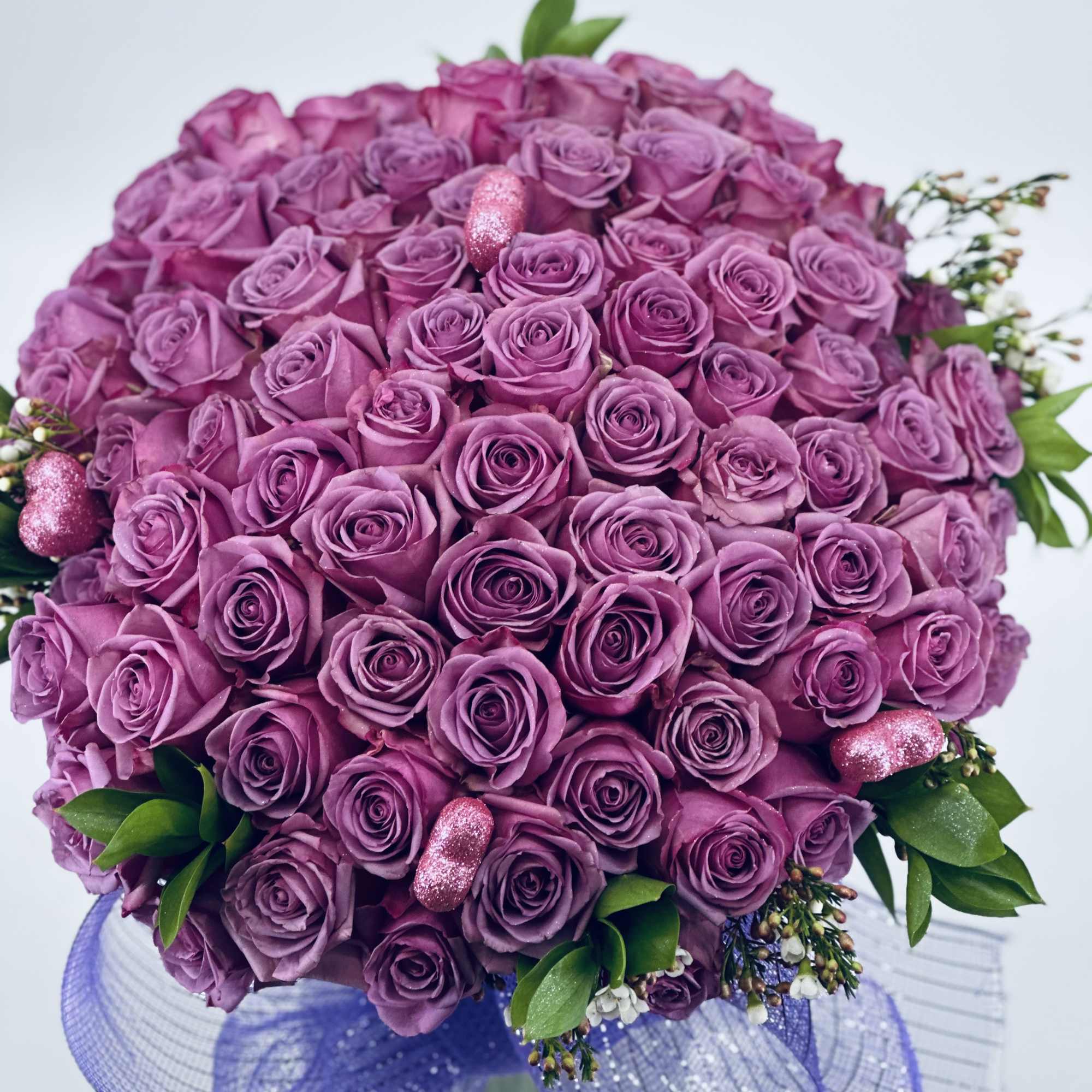 Round bouquet of purple roses with glittery accents and purple ribbon