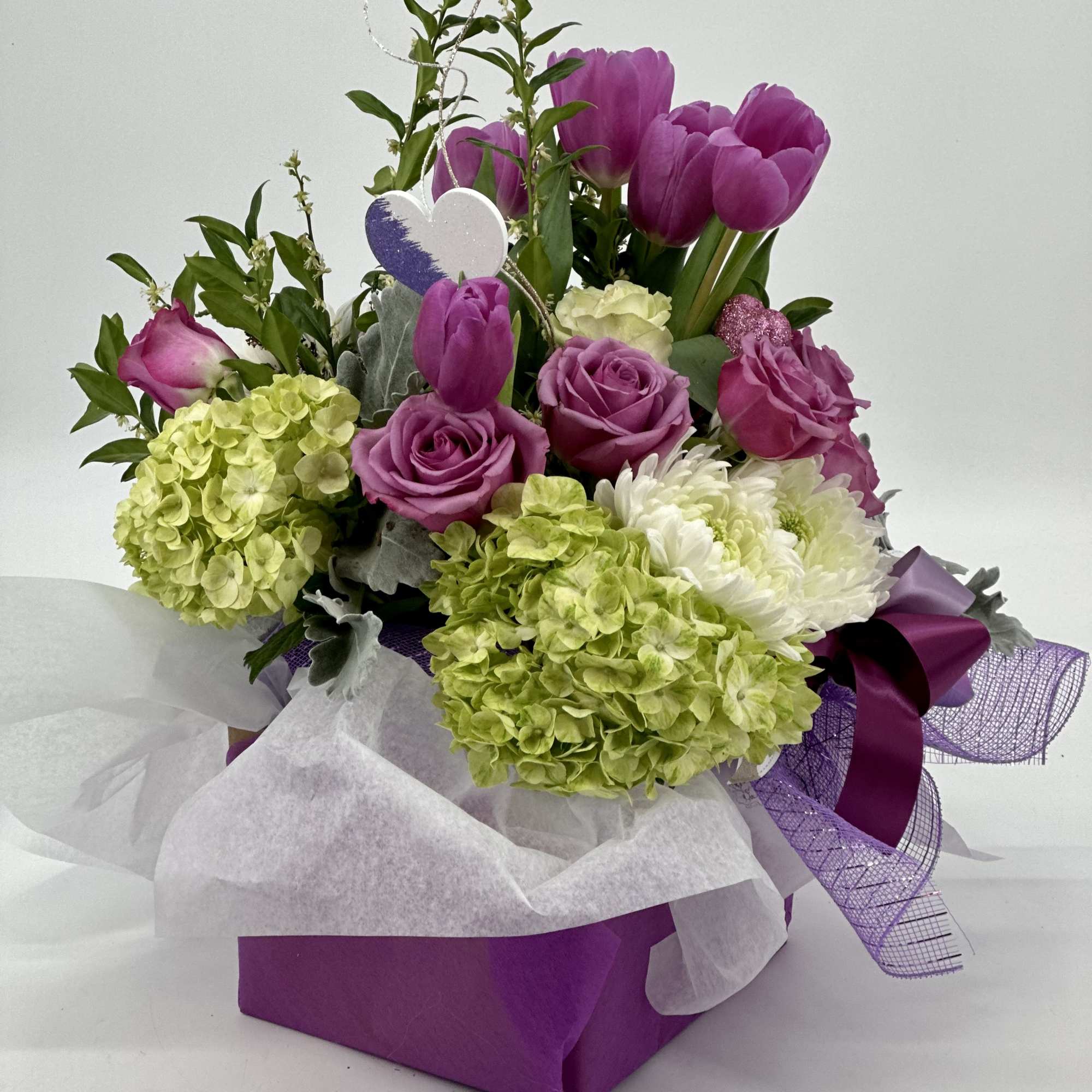 Bouquet of purple tulips, roses, and hydrangeas in a purple gift box