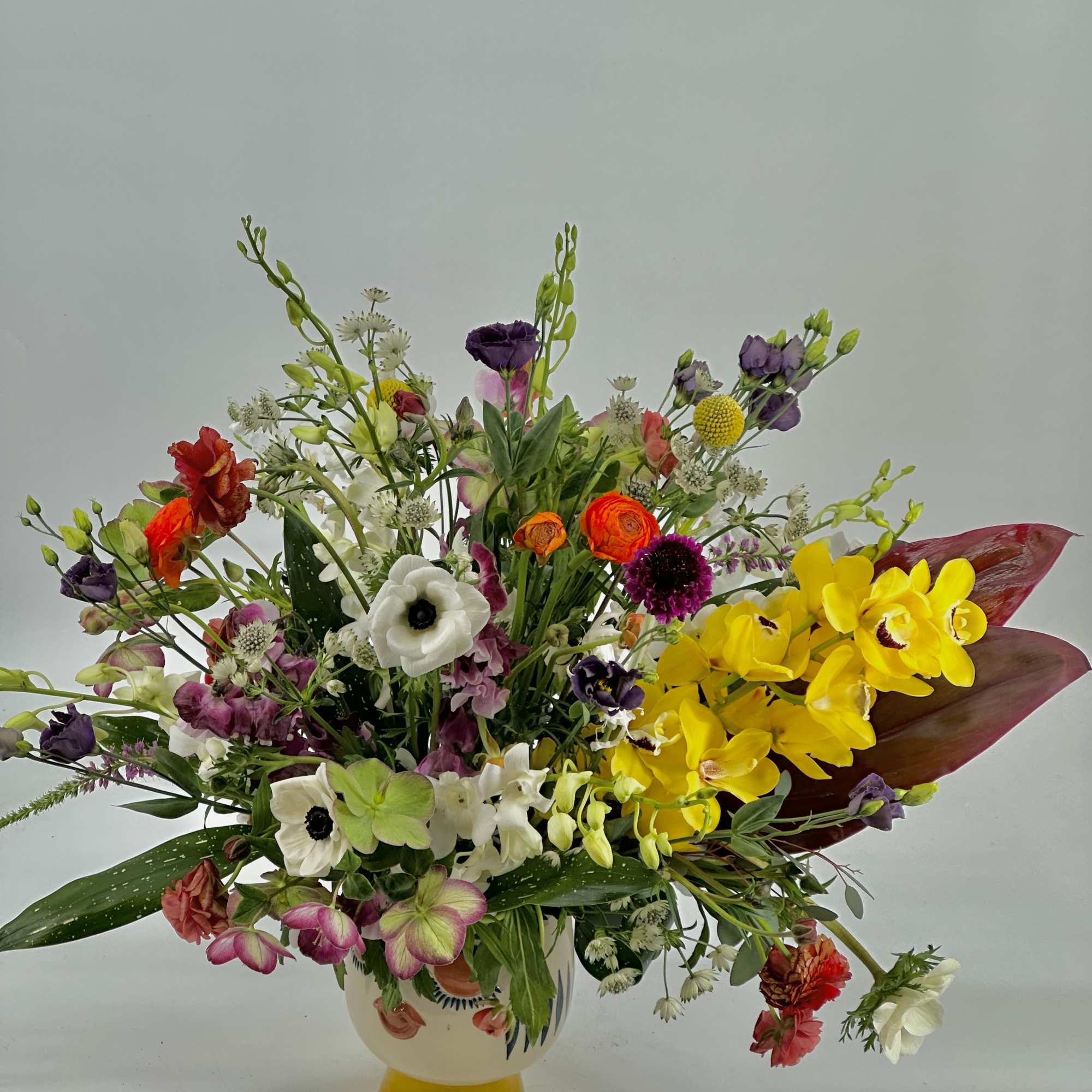 Mixed bouquet in a white vase with bright yellow orchids and purple blooms