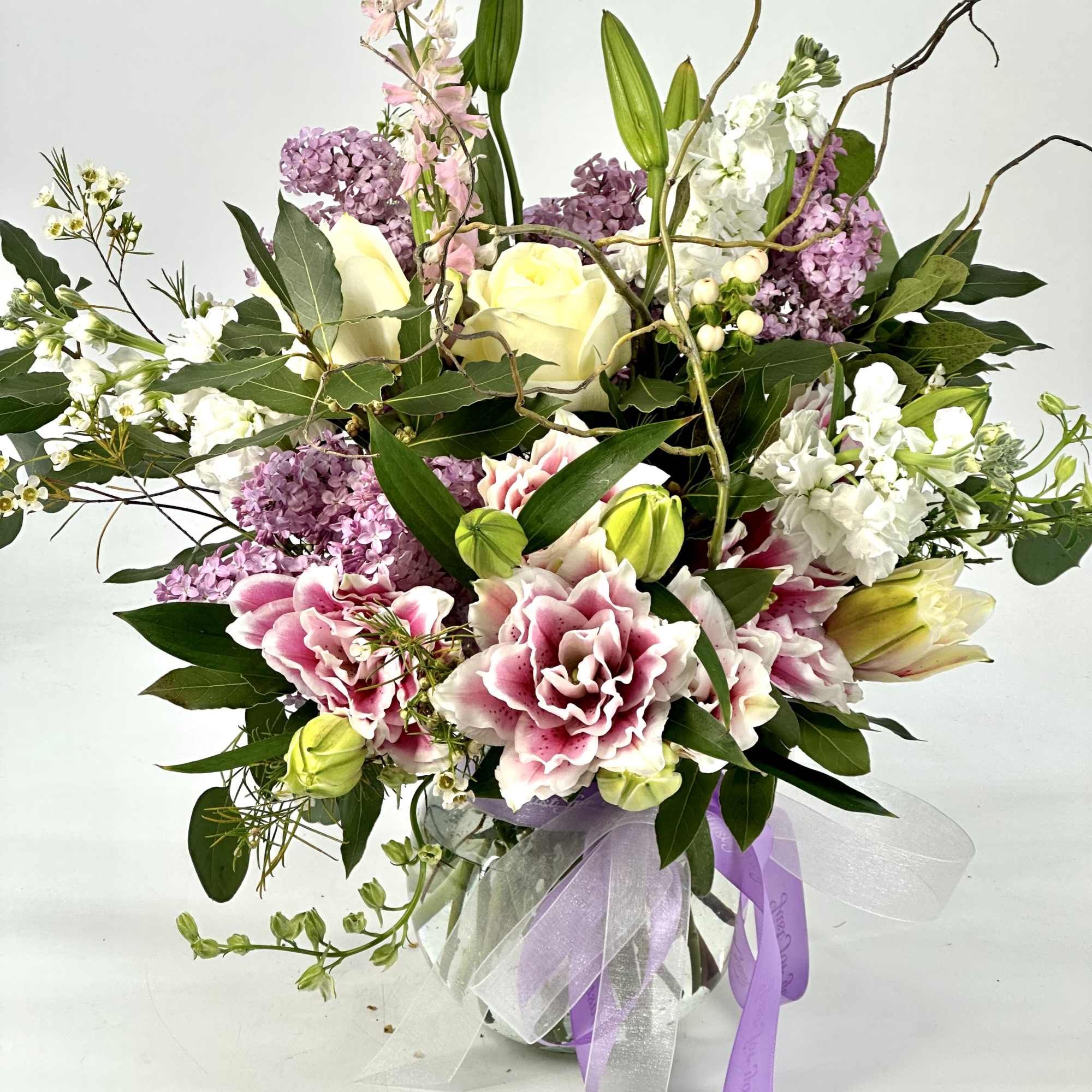 Pink and white floral arrangement in a glass vase with ribbon