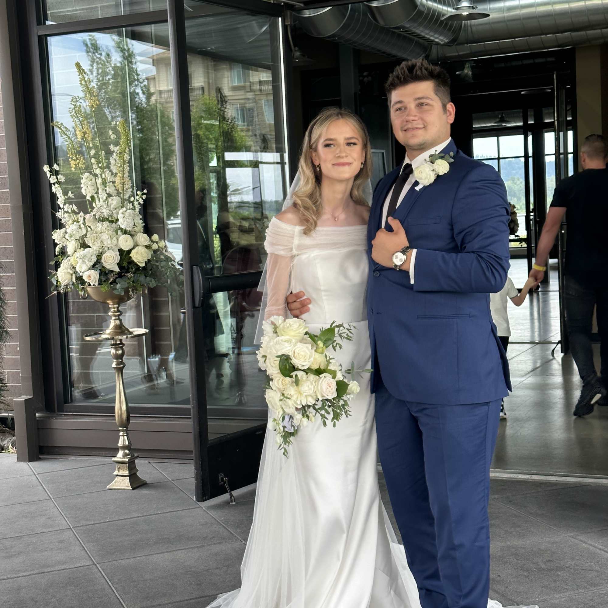 Bride and groom with white floral bouquet and tall ceremony arrangement