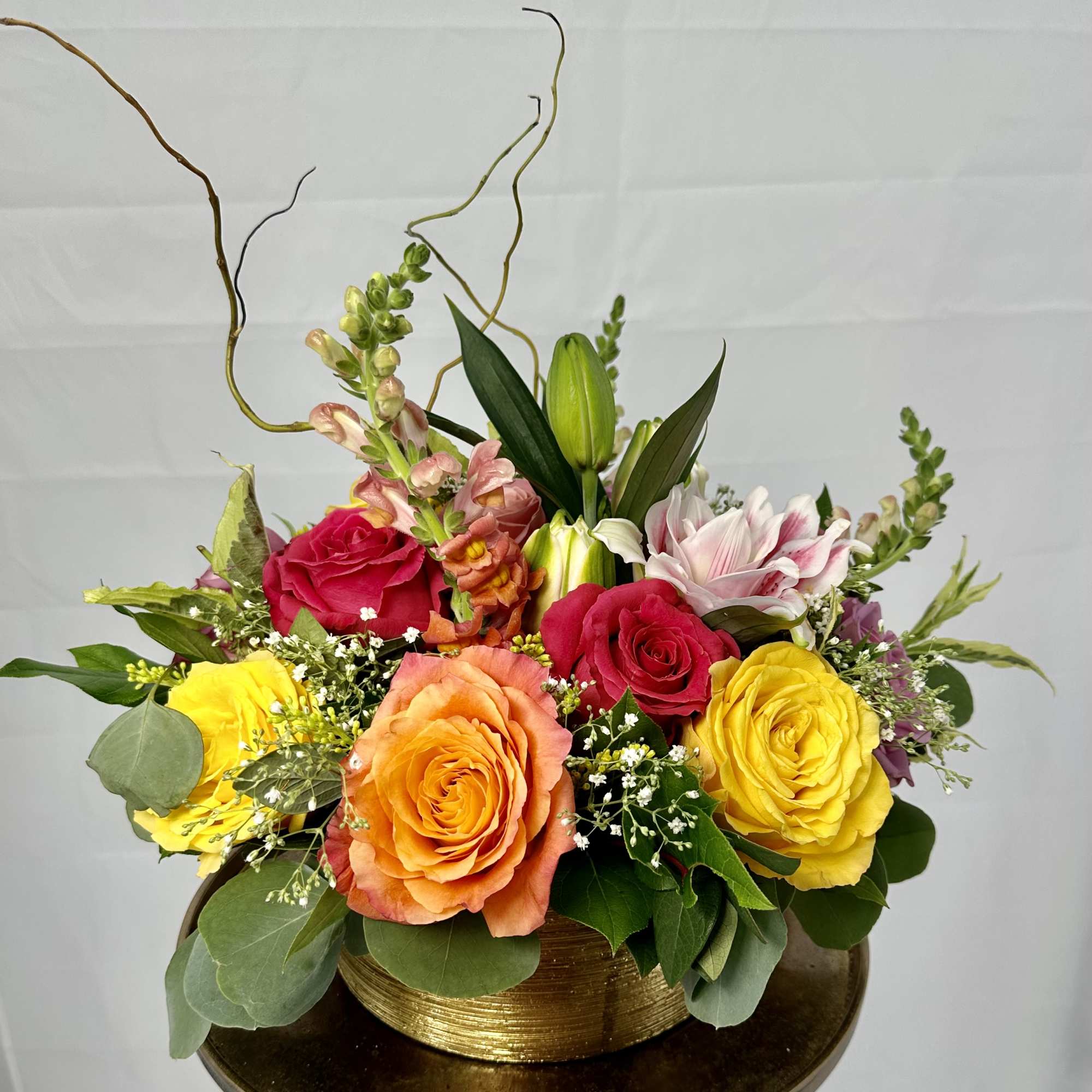 Mixed bouquet of roses and lilies in a gold container