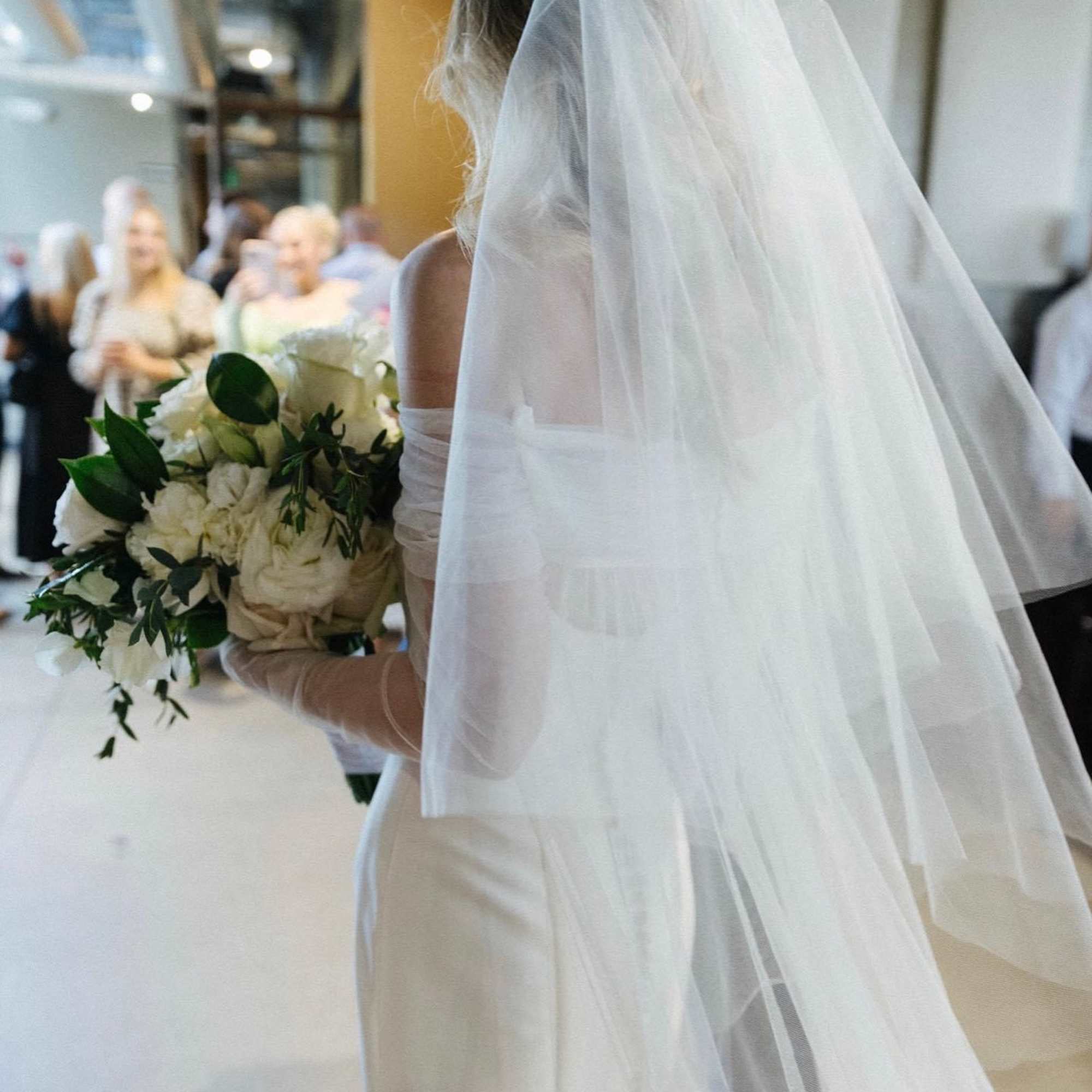 Bride holding a white bouquet with greenery