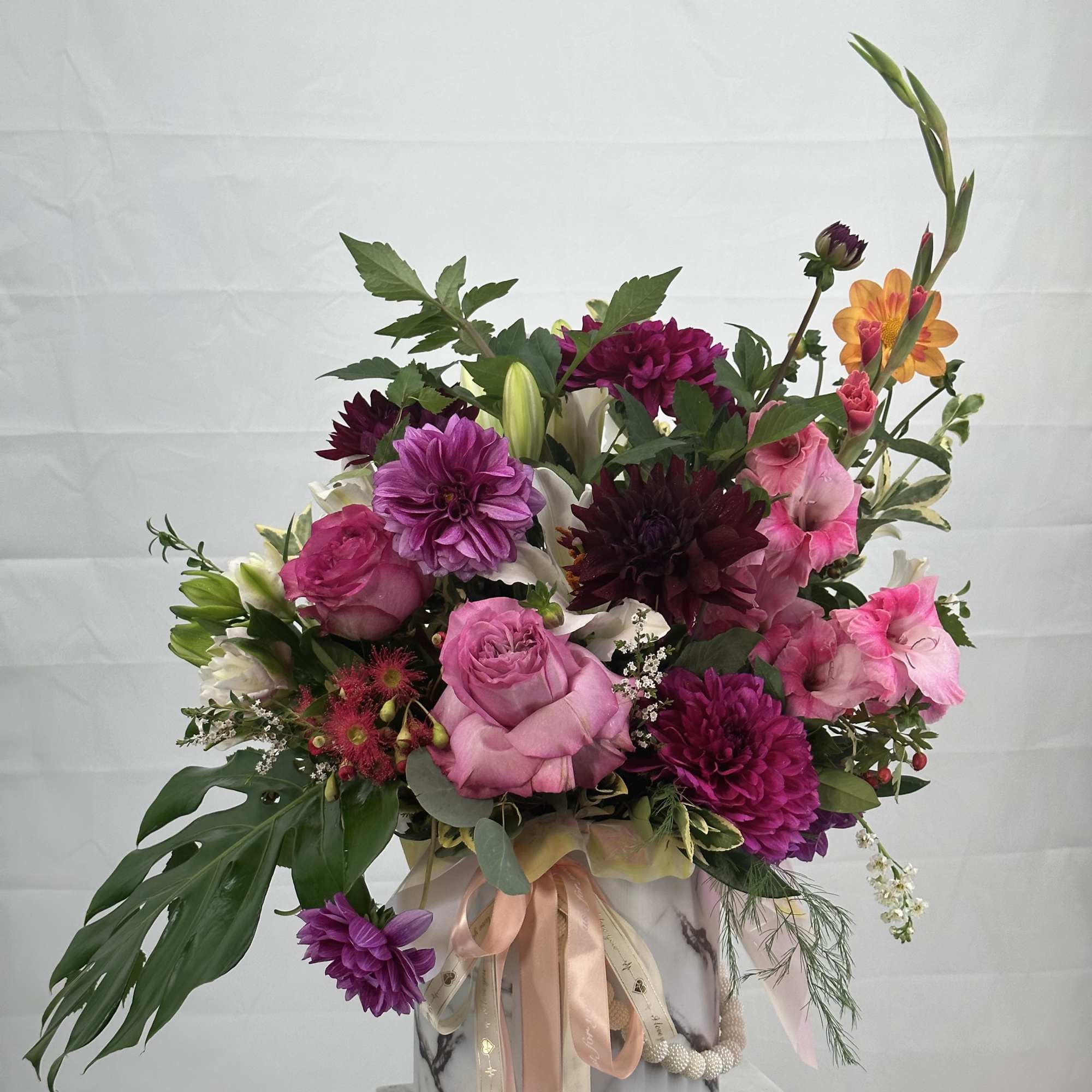 Pink and purple mixed bouquet in a marble-patterned box with ribbons
