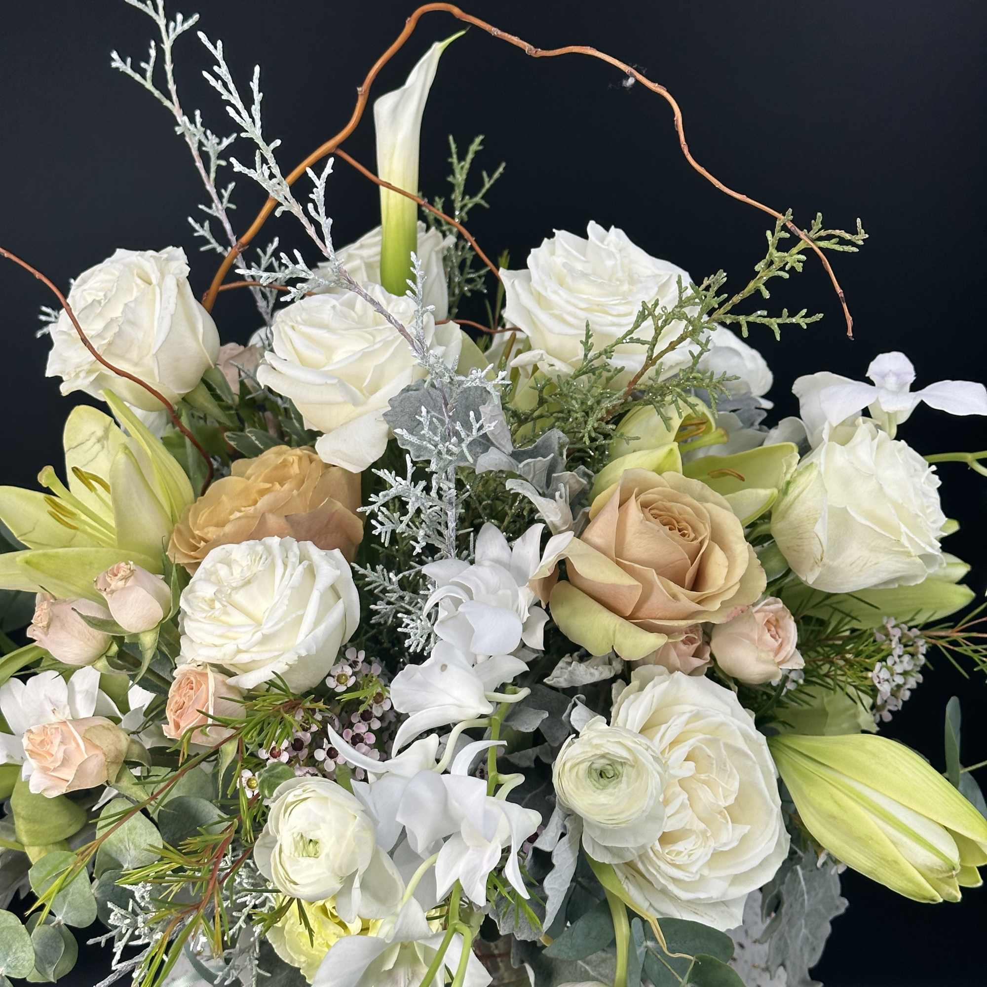 White and blush floral arrangement in a speckled vase with mixed blooms and branches