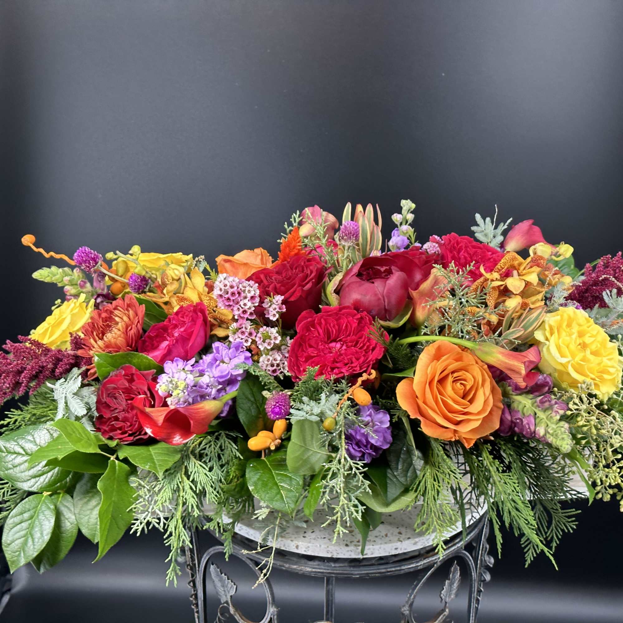 Low floral centerpiece with roses, carnations, and mixed blooms in bright colors