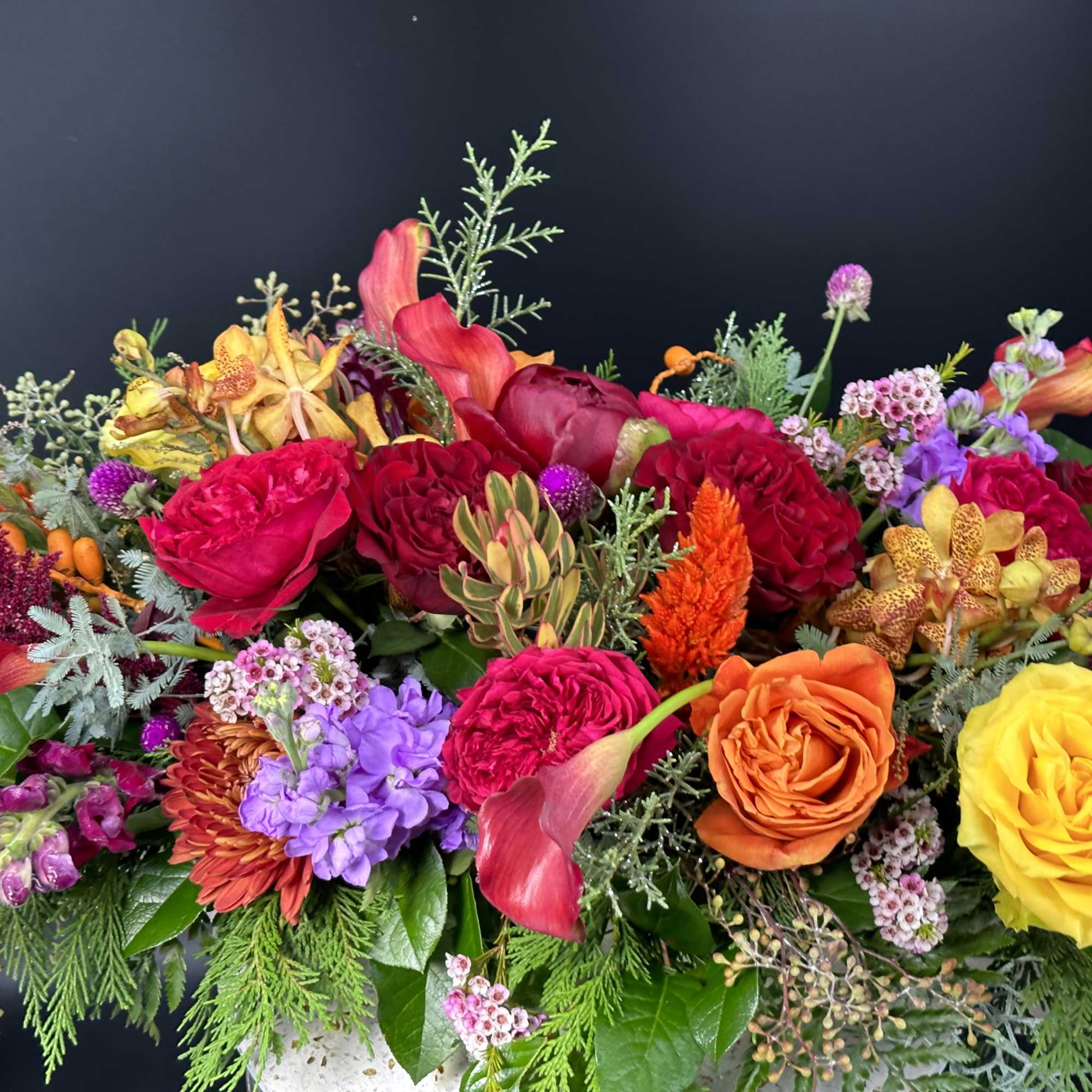 Bright mixed floral arrangement with roses, calla lilies, and orchids