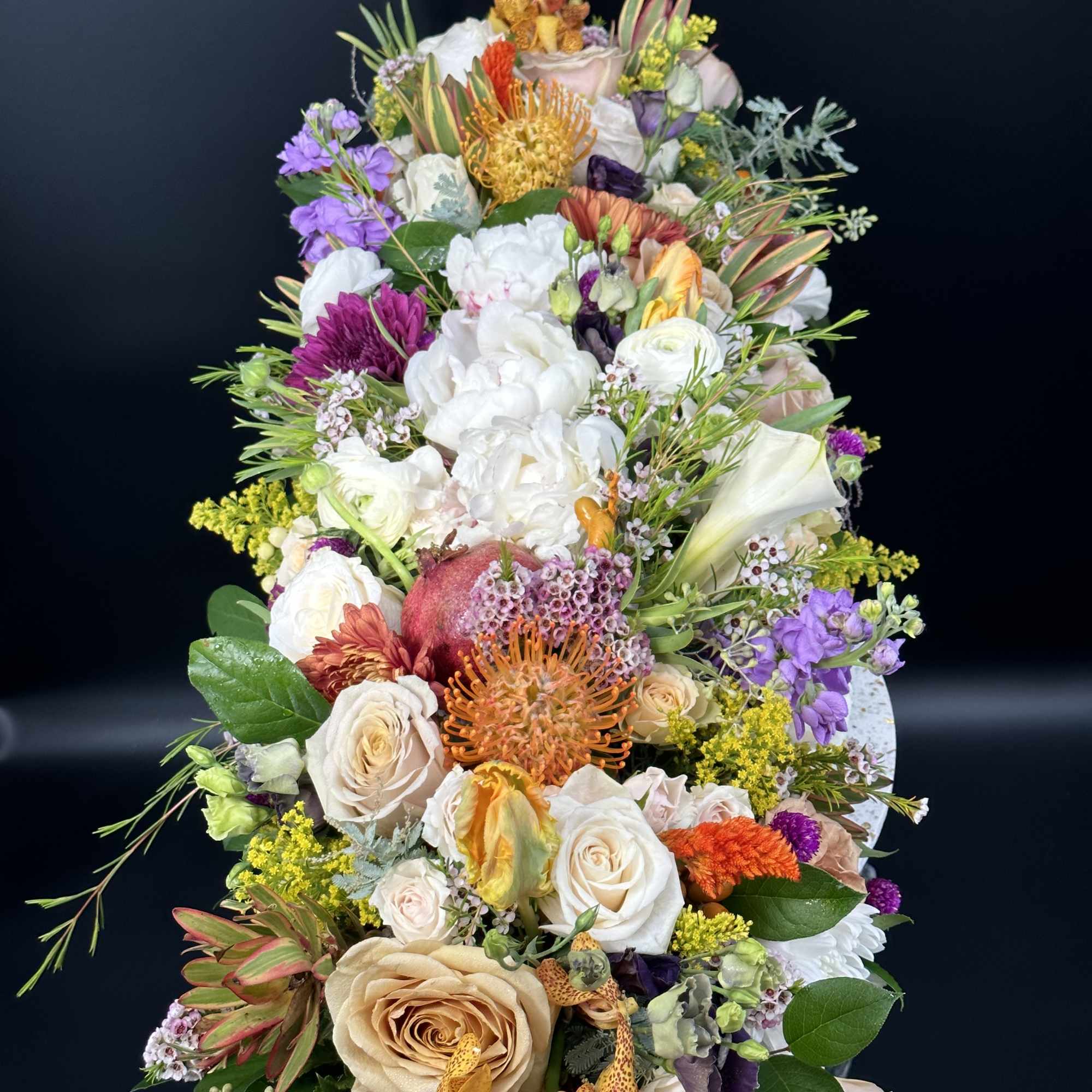 Tall mixed floral arrangement with white, peach, purple, and orange blooms
