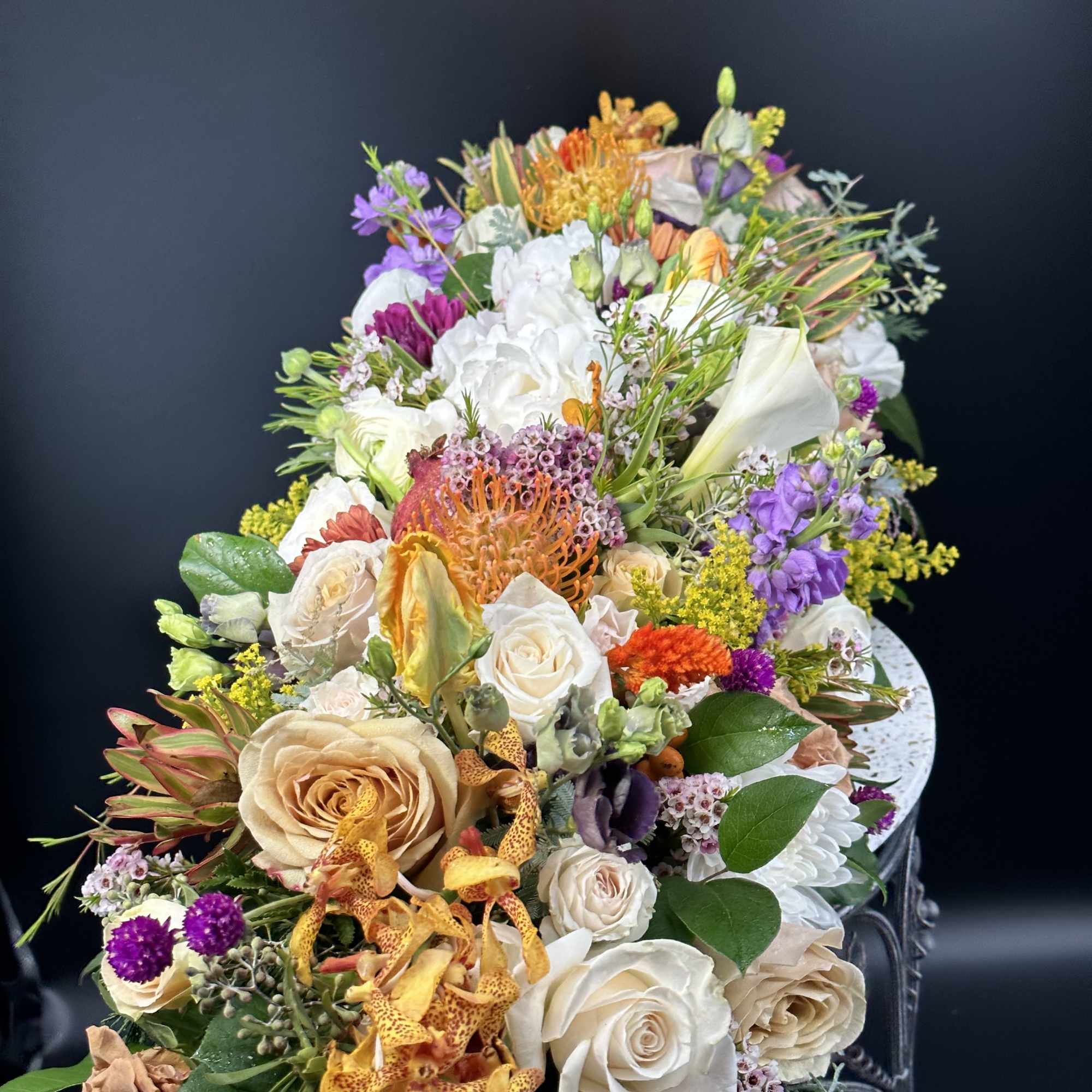 Large mixed floral arrangement with white, peach, purple, and orange blooms